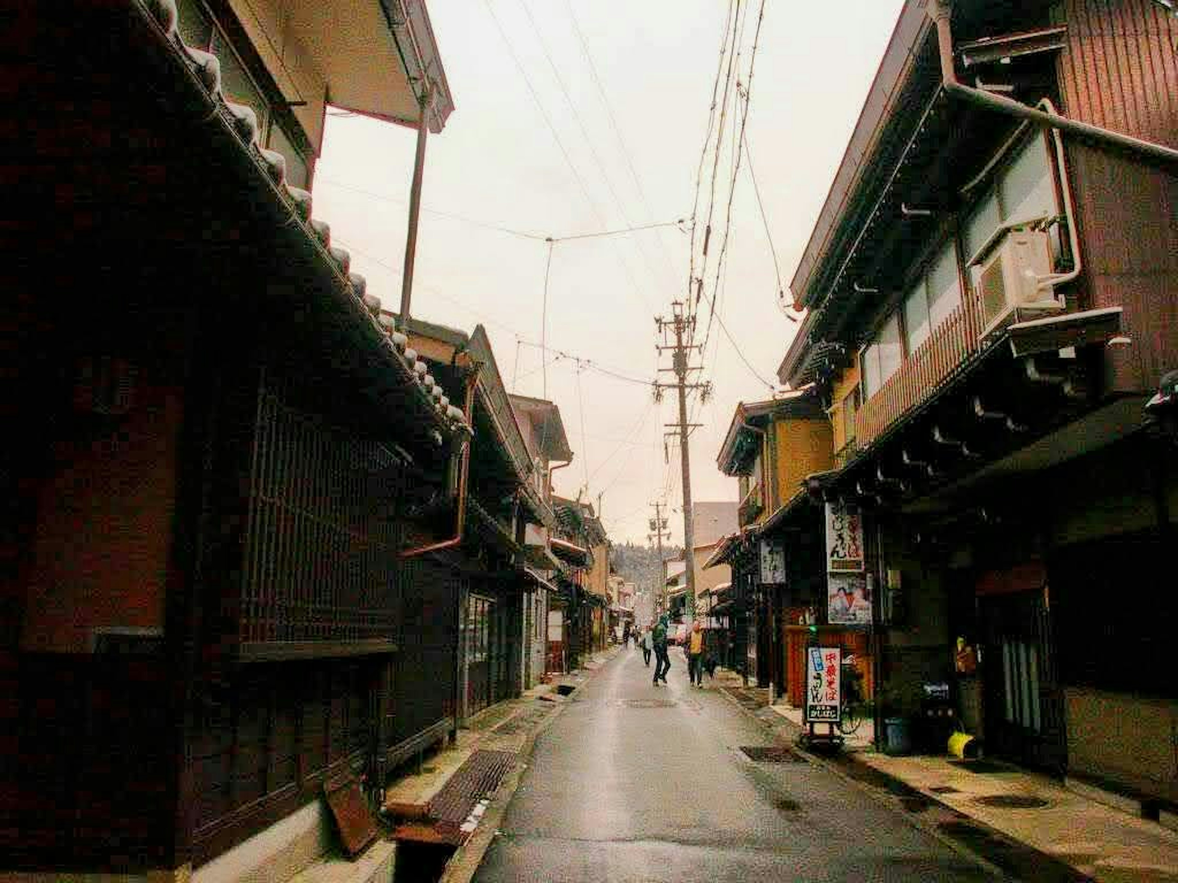 Jalan Jepang yang tenang dipenuhi bangunan kayu tradisional dan tiang listrik