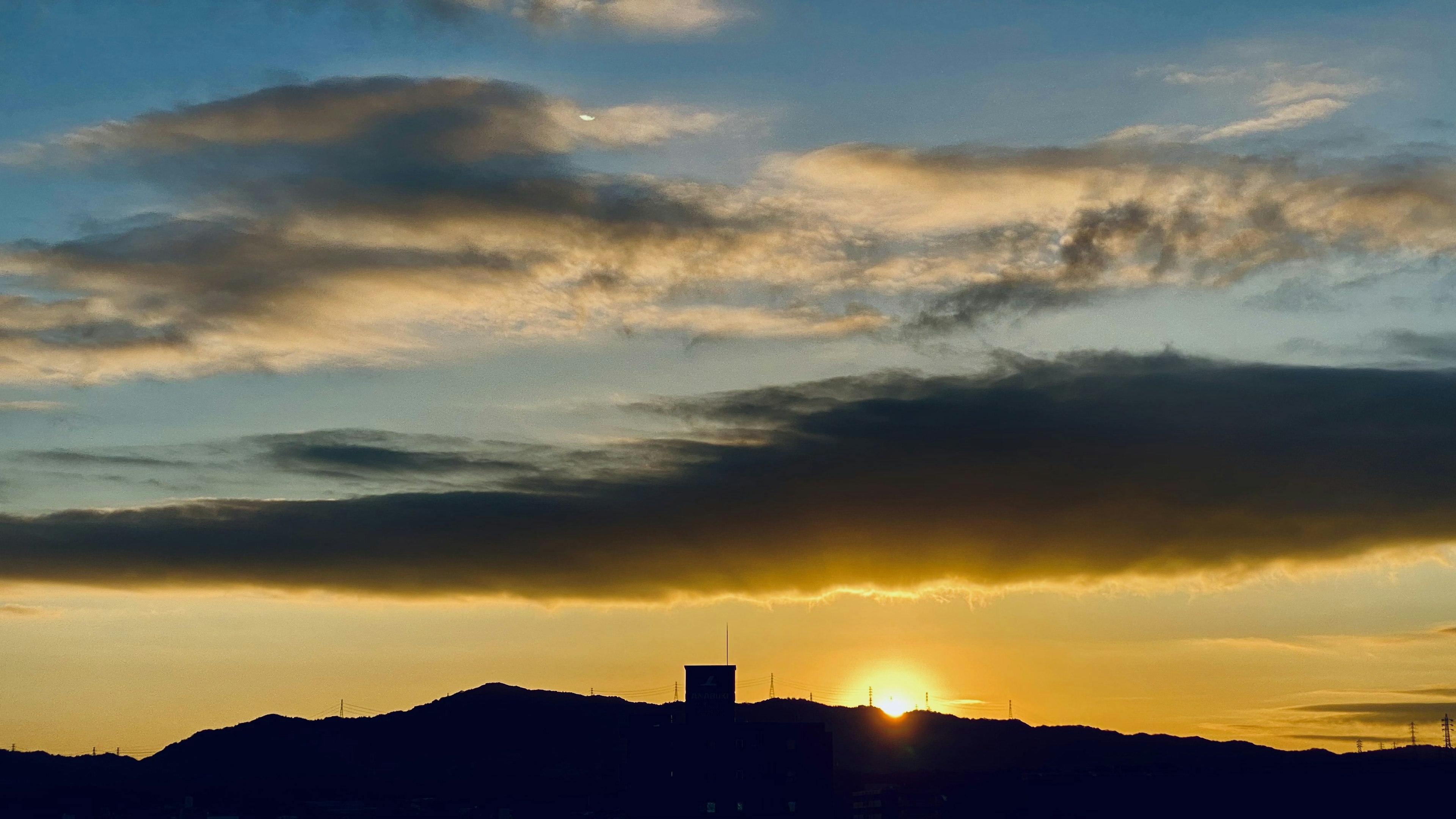 Silueta de montañas con un sol poniente y nubes coloridas