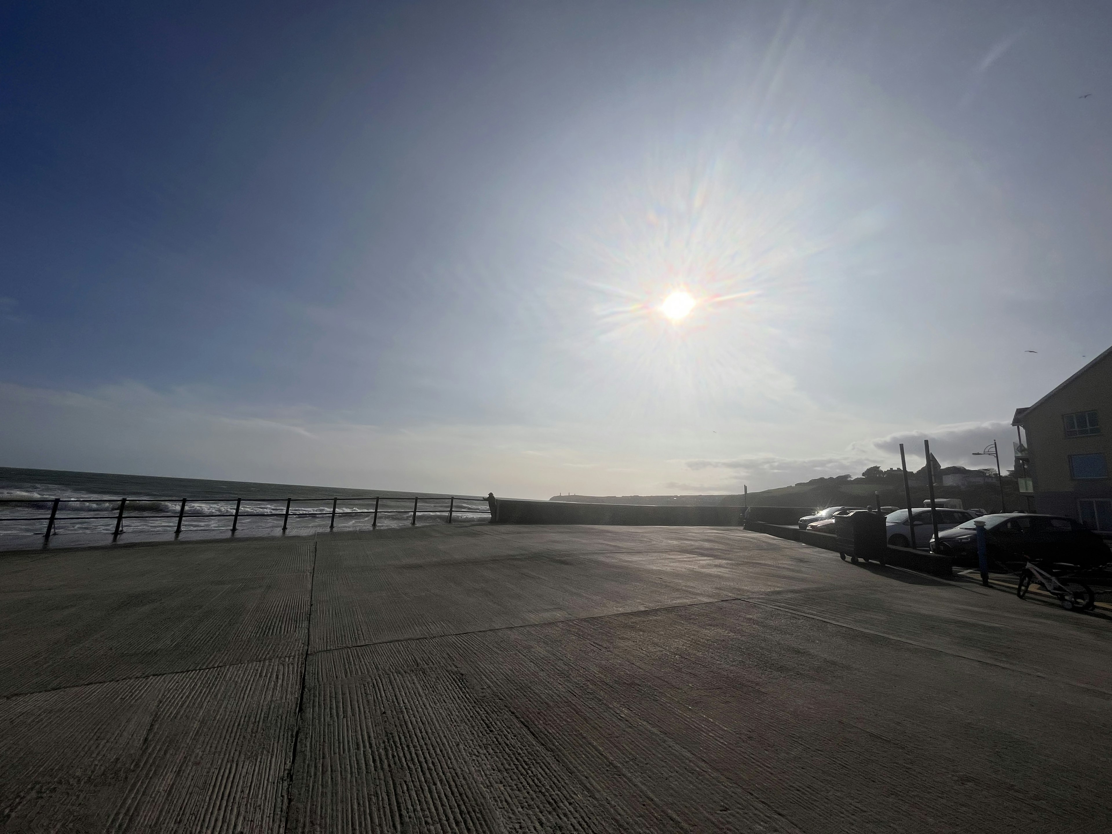 海岸沿いの広い歩道と青い空に浮かぶ太陽