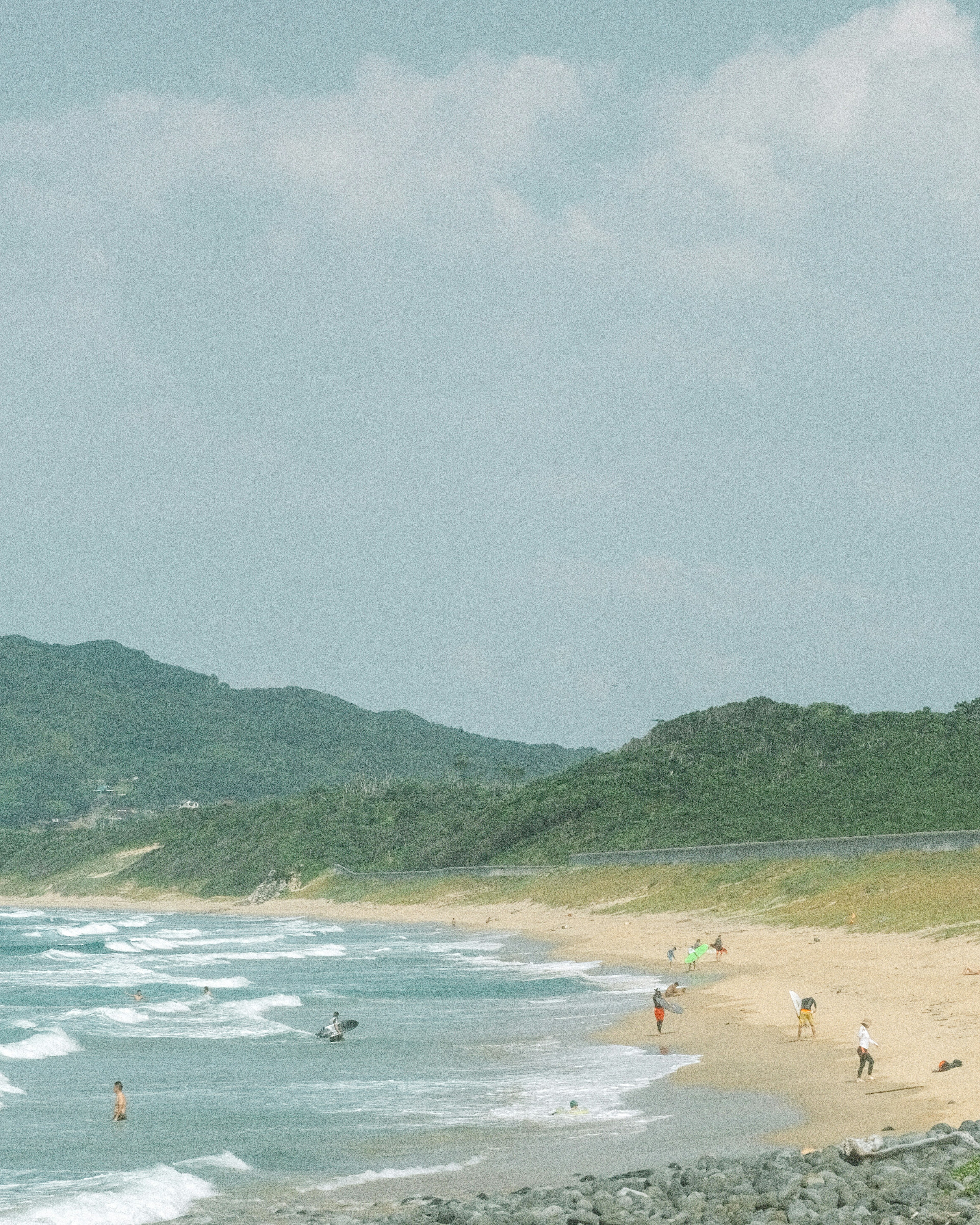 风景如画的海滩，游客在海岸享受温和的海浪