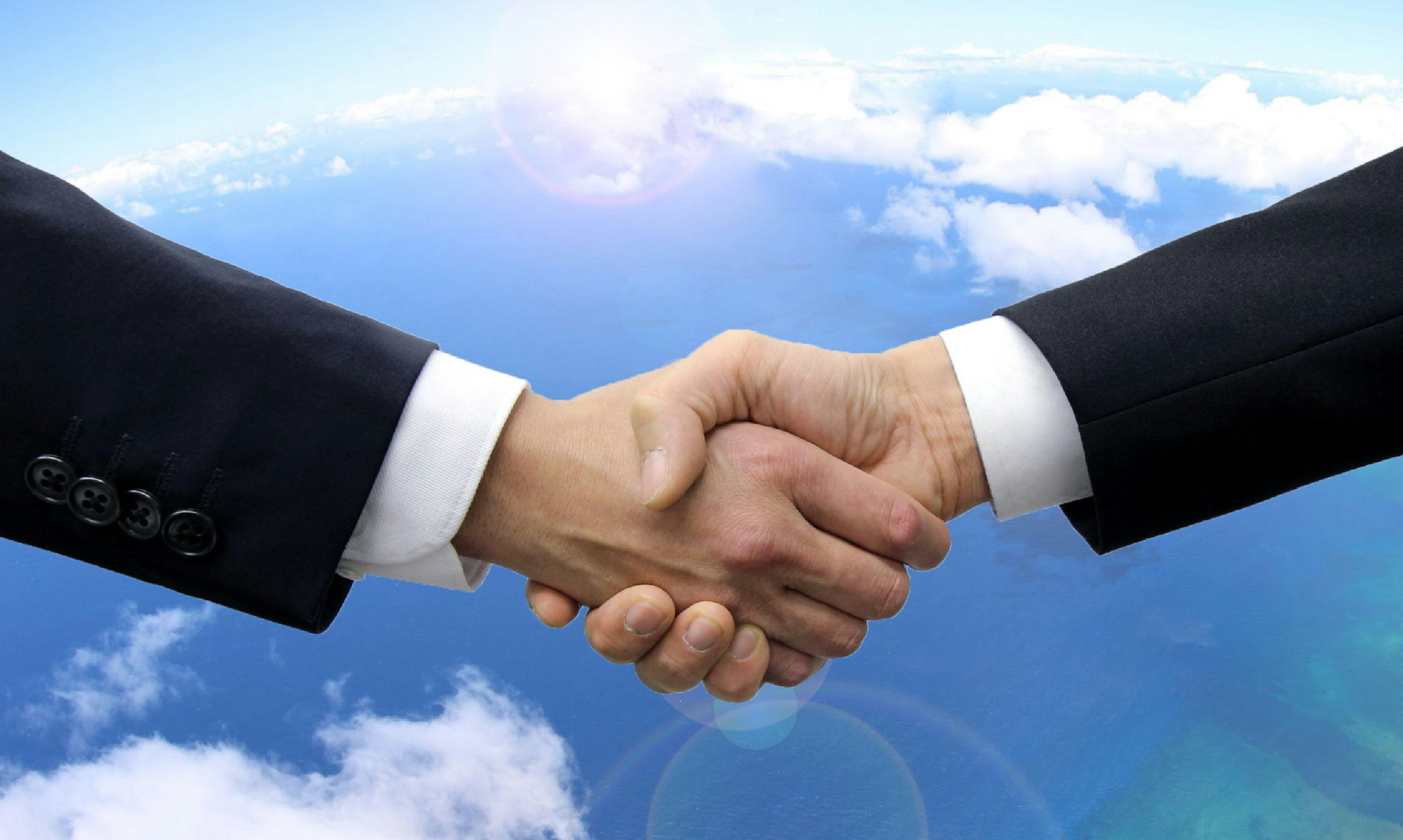 Businessmen shaking hands under a blue sky