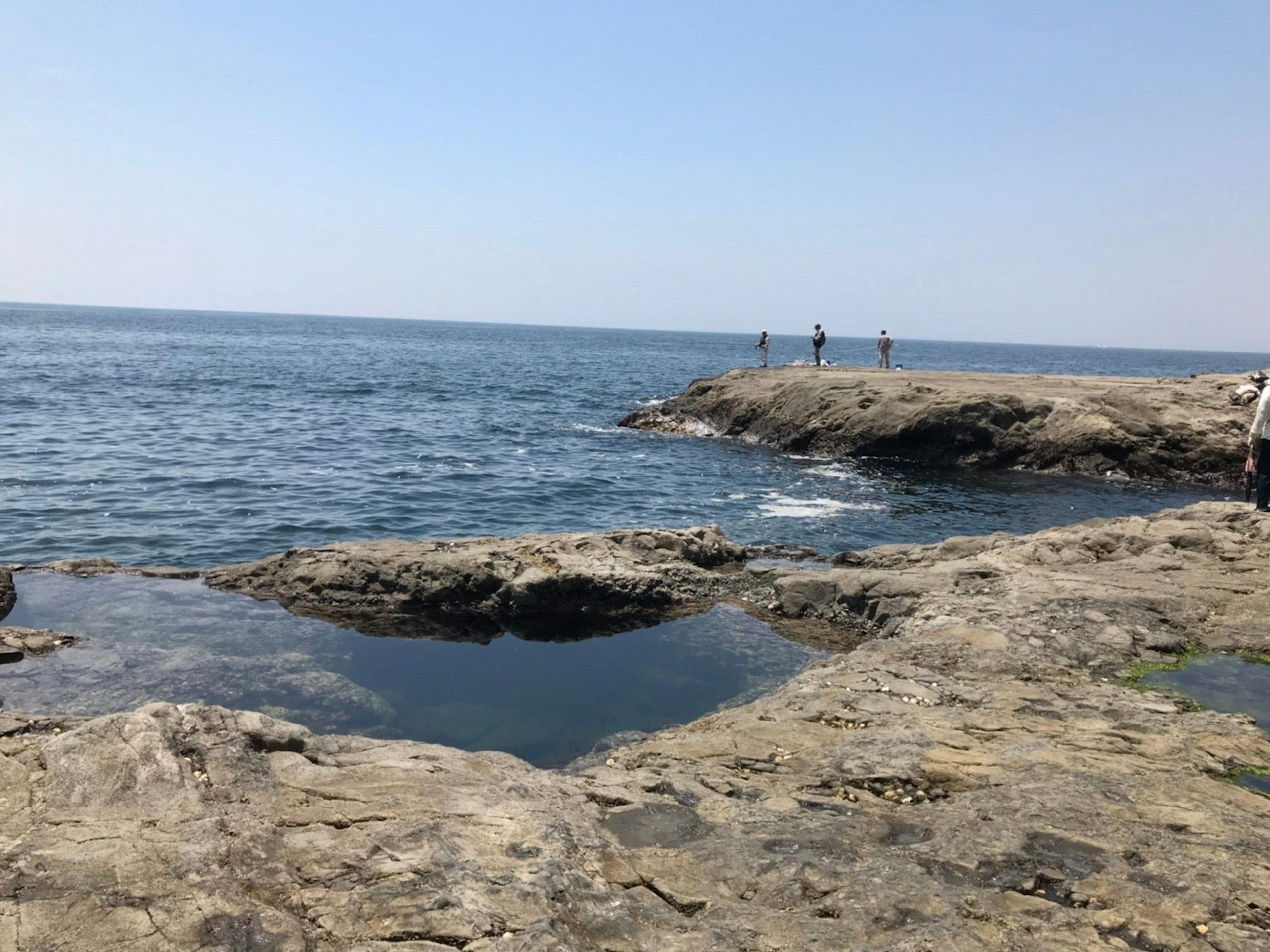 Coastal scene with rocky shoreline and people in the distance