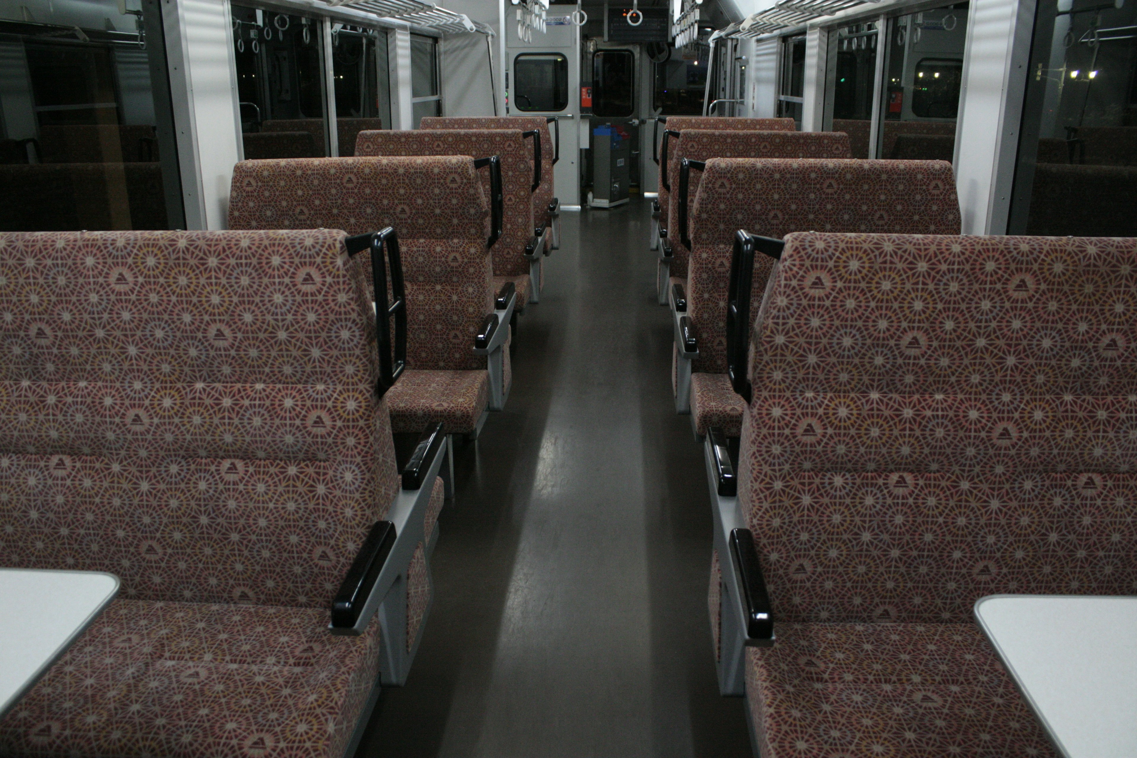 Interior view of an empty train carriage with patterned seats and tables