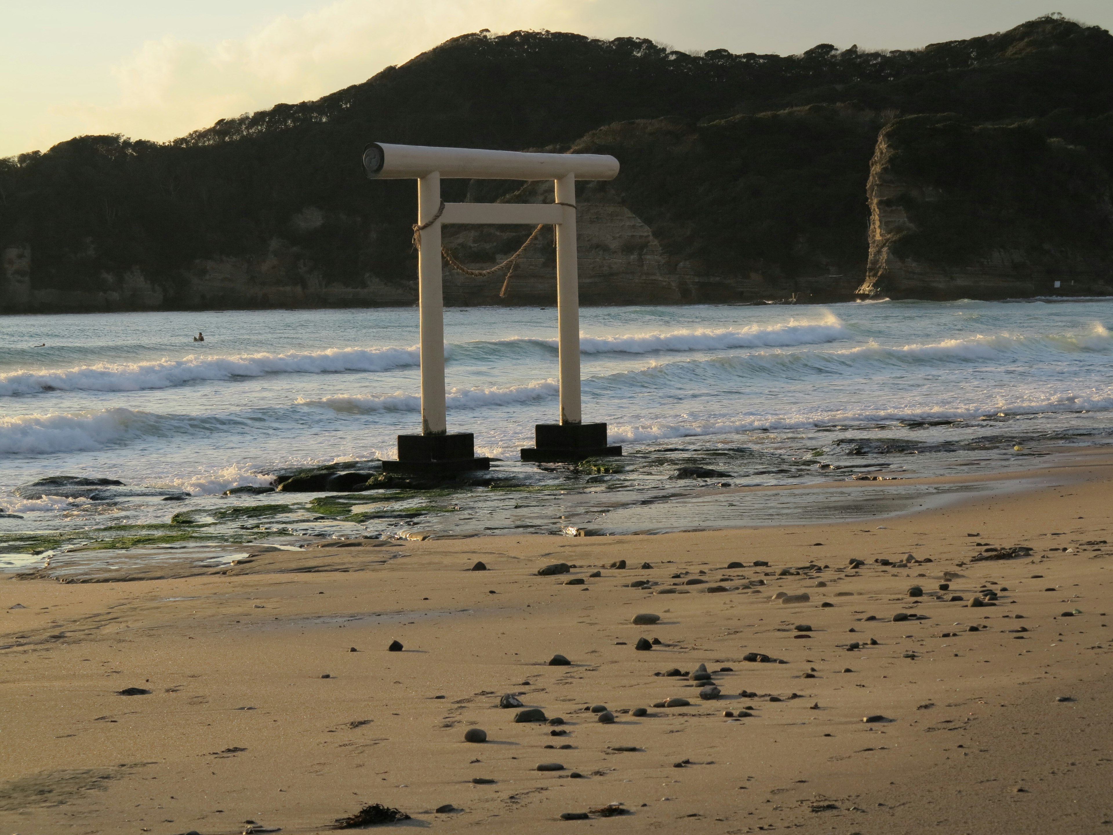 Cổng torii trắng gần bãi biển với sóng