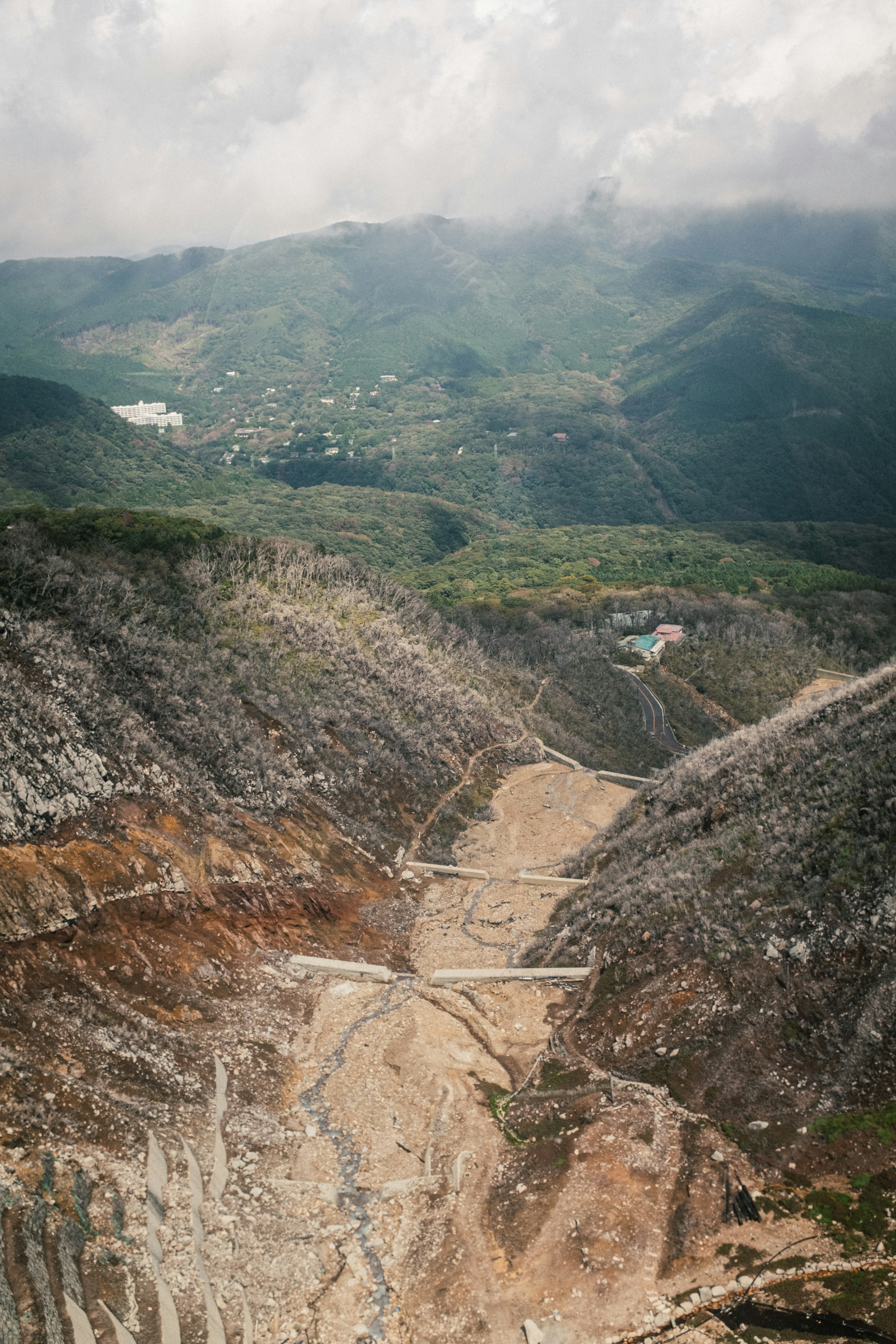 Expansive view of a mountainous valley with green hills and a cloudy sky