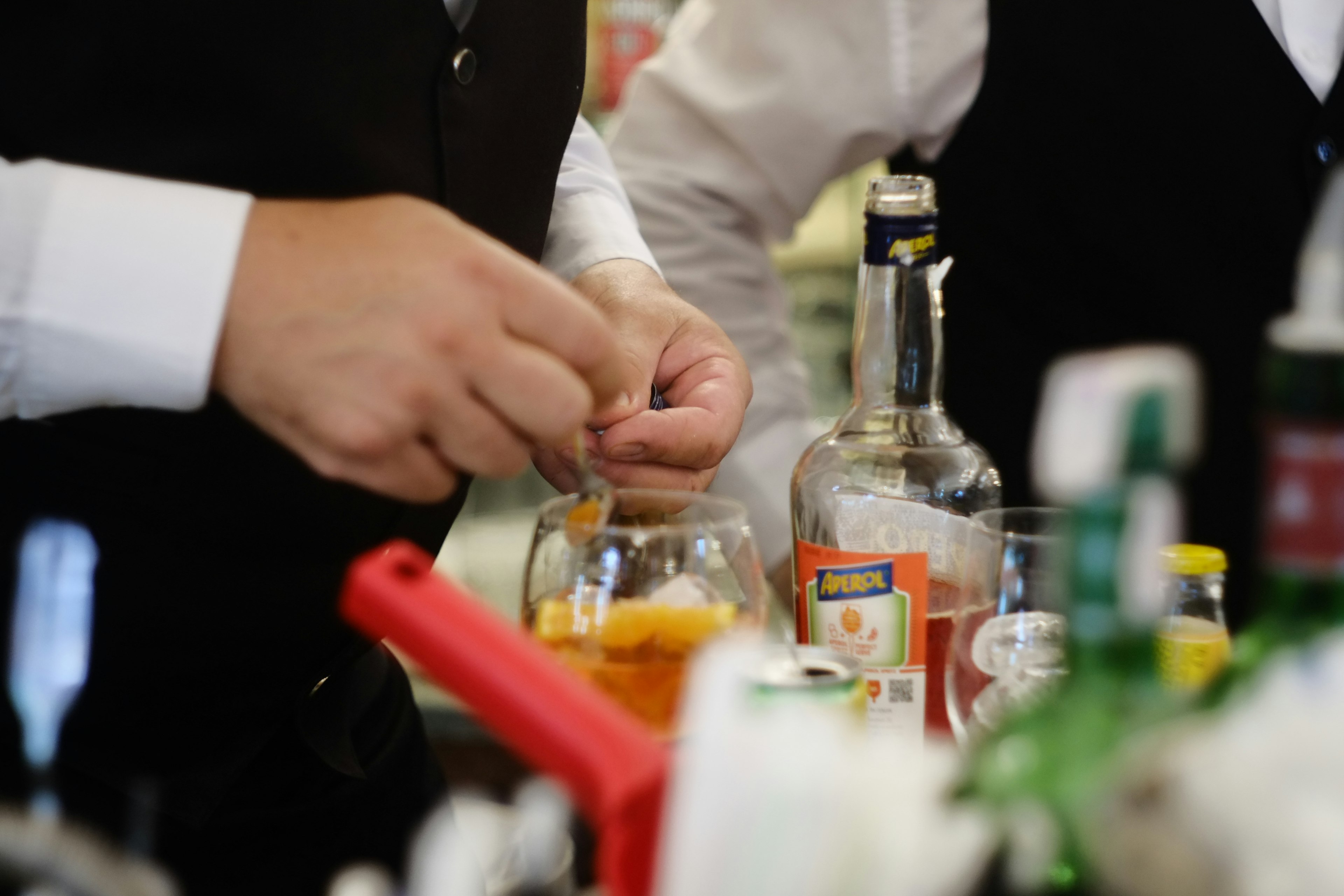 Bartender preparing a cocktail with orange slices visible