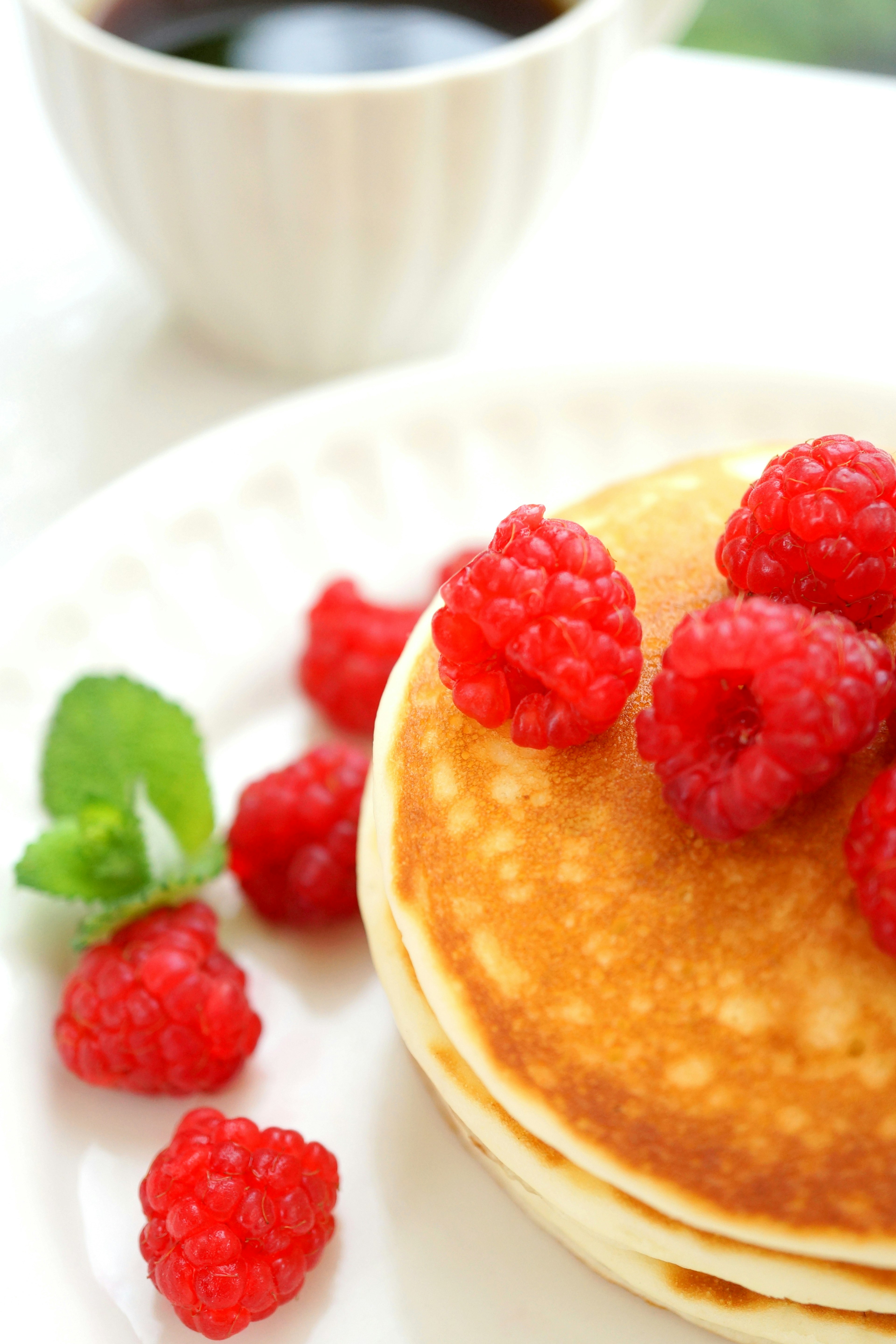 Pancakes moelleux garnis de framboises fraîches et de feuilles de menthe