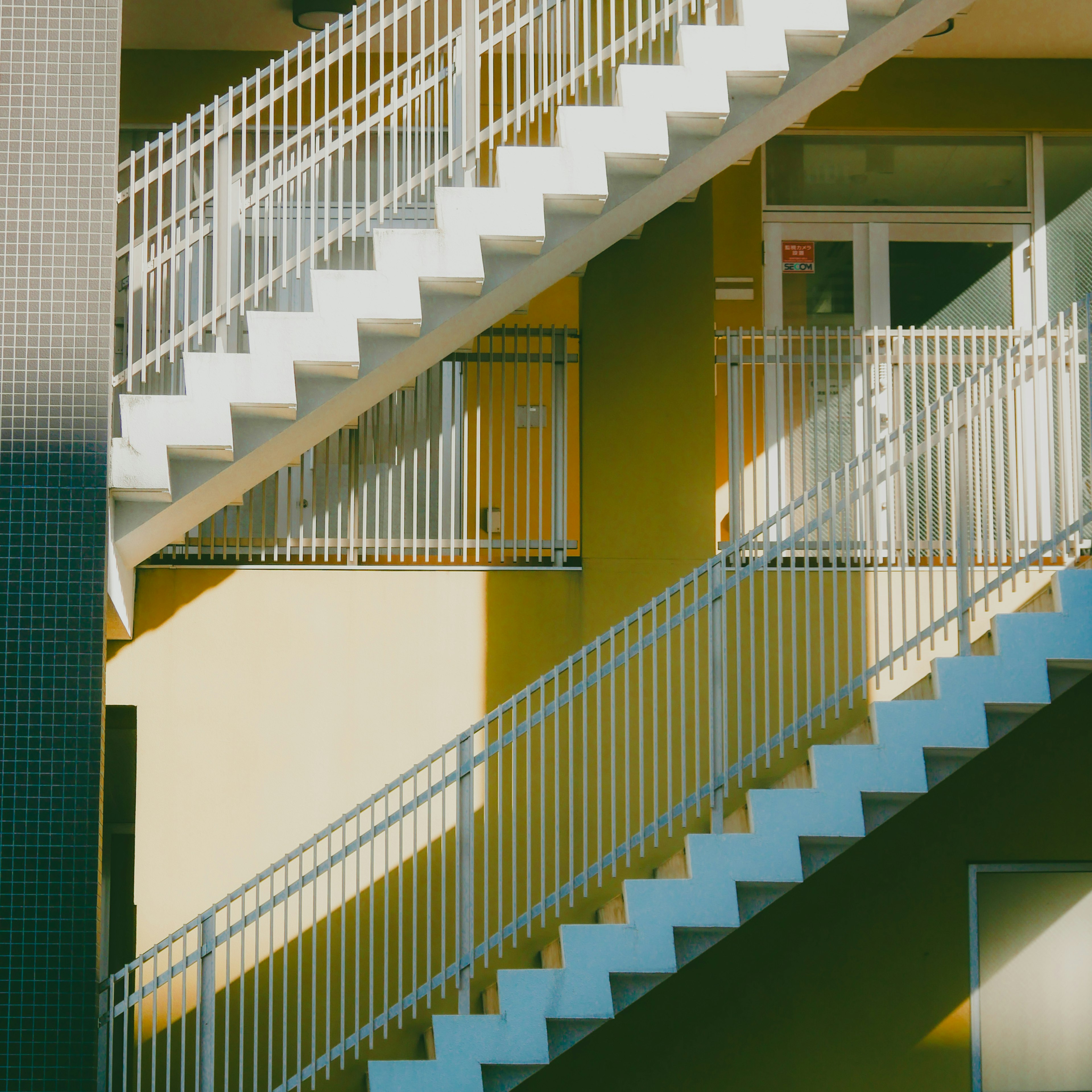 Staircase with white railings and yellow walls in a modern building