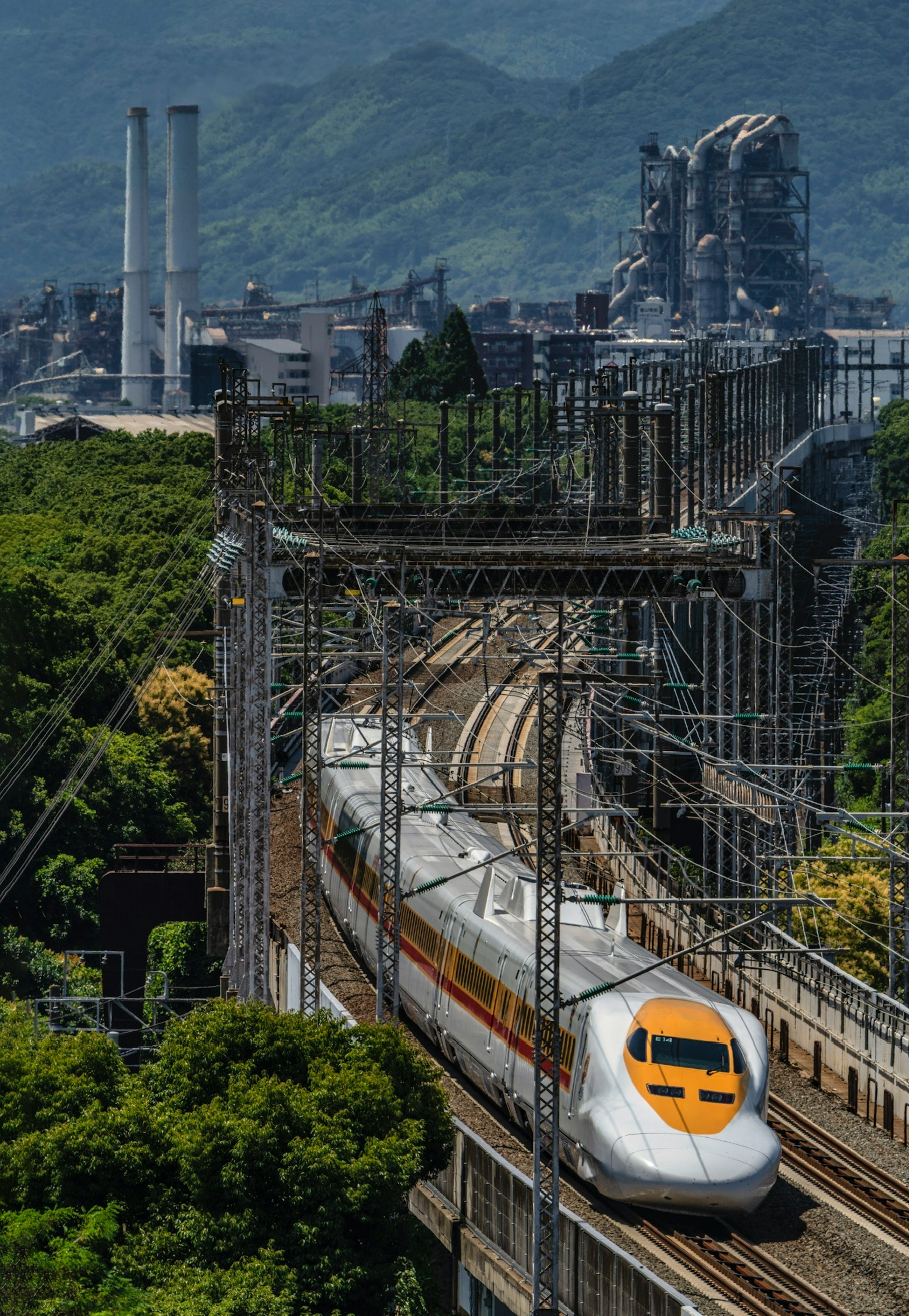 新幹線が緑の山々を背景に橋を渡る風景