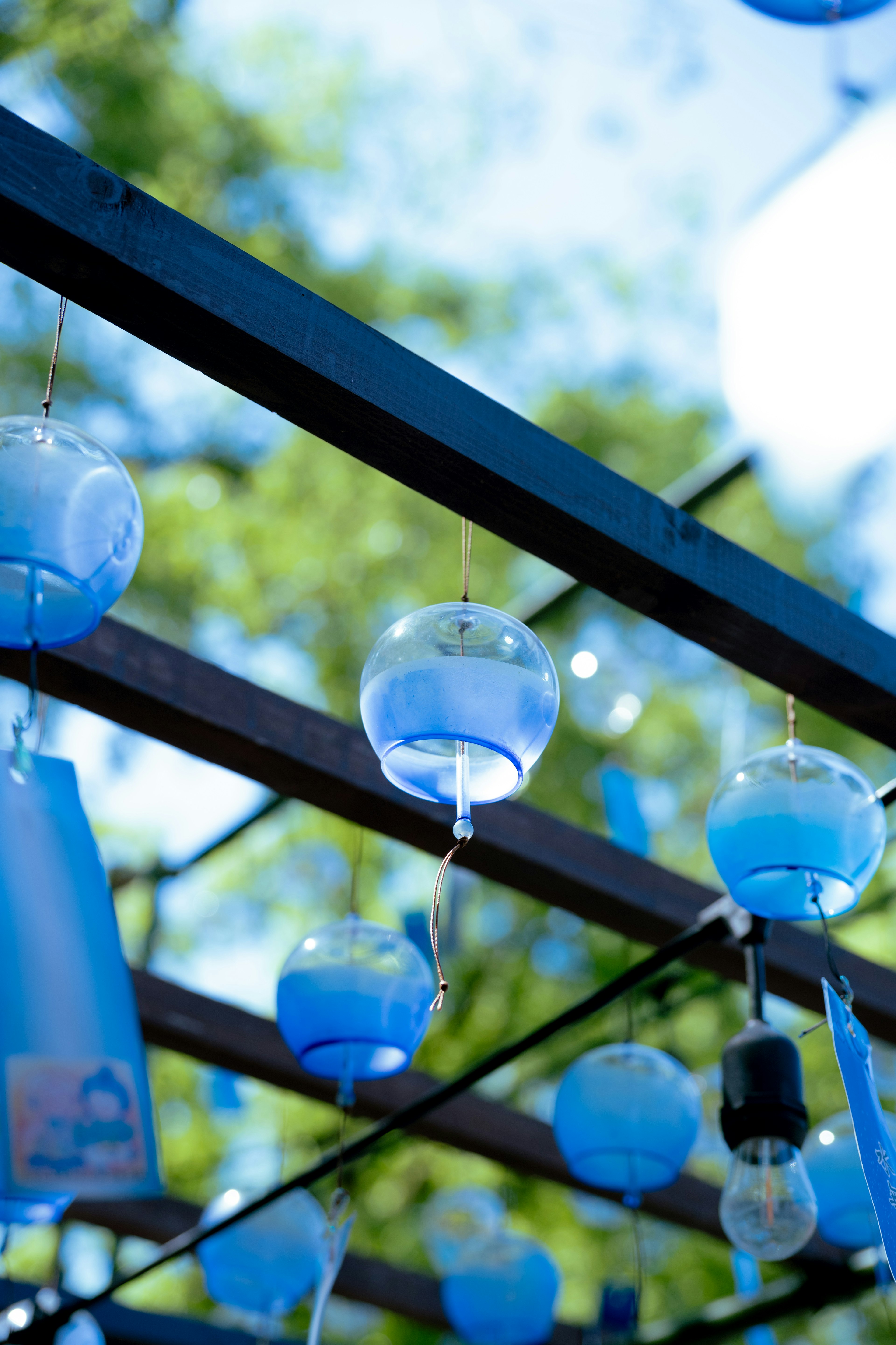 Blue wind chimes hanging from a wooden structure