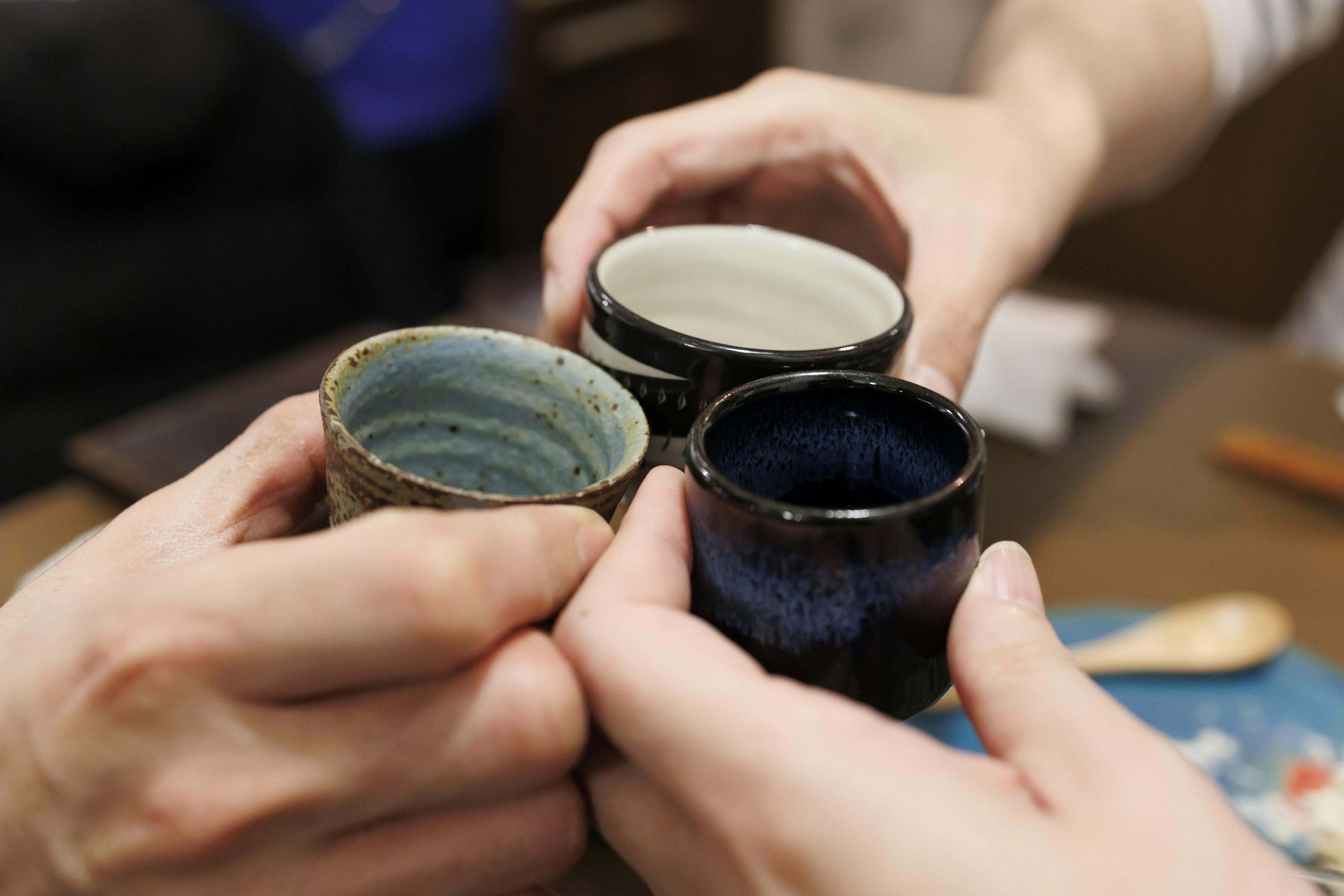 Hands holding three different colored cups toasting together