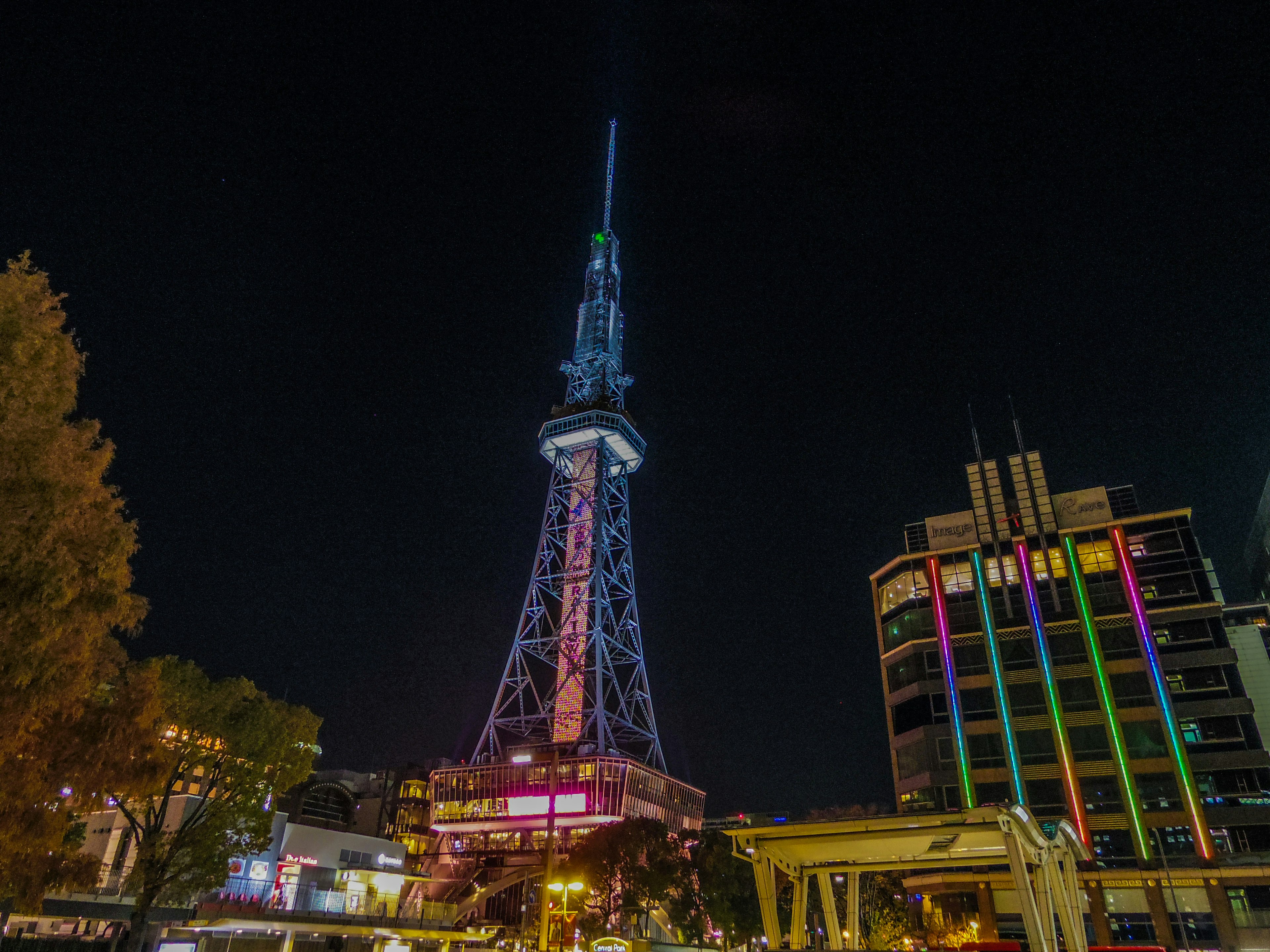 Nagoya Fernsehturm bei Nacht mit bunten Lichtern und nahegelegenen Gebäuden