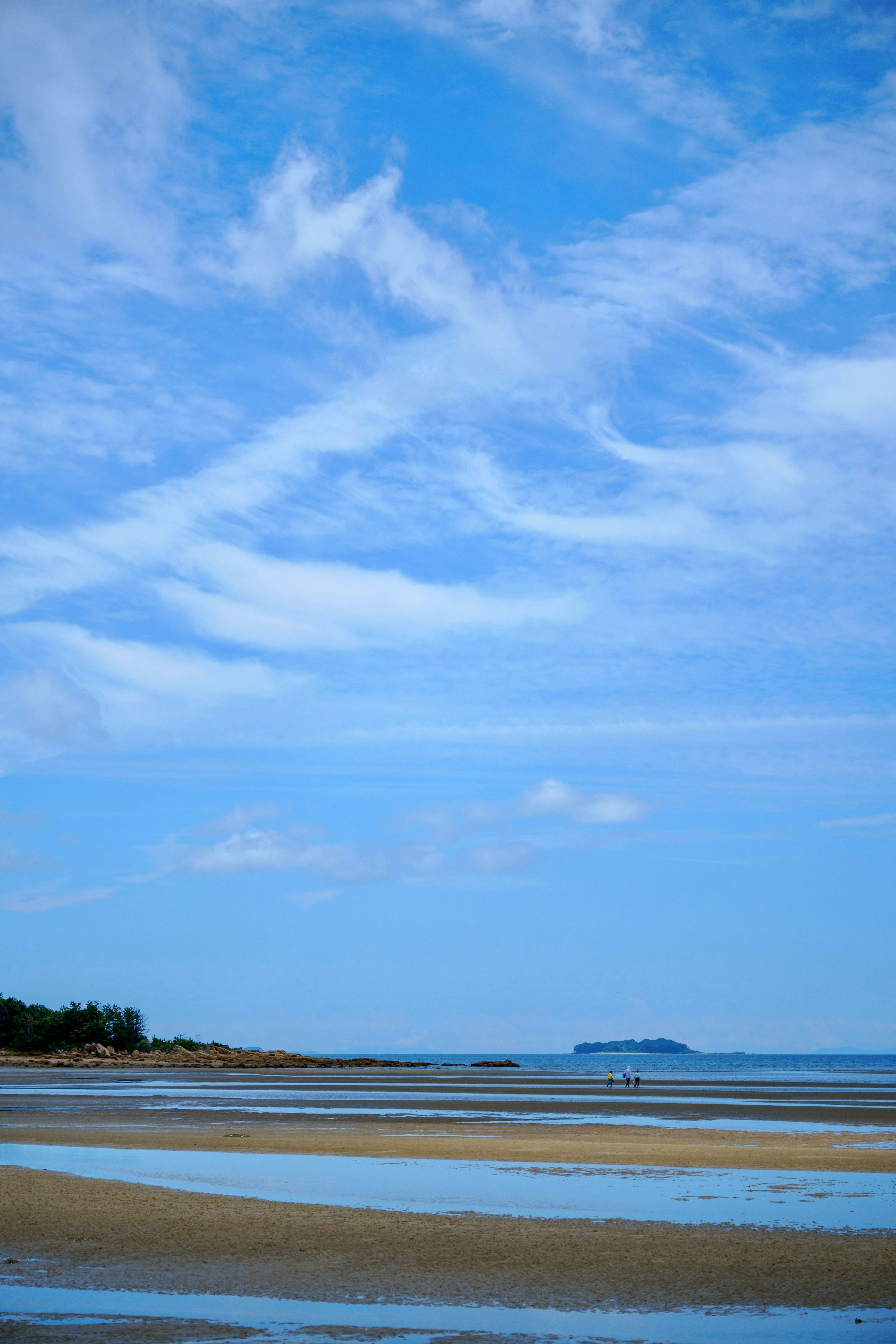 Pemandangan pantai dengan langit biru dan awan pantai berpasir dan pulau jauh terlihat