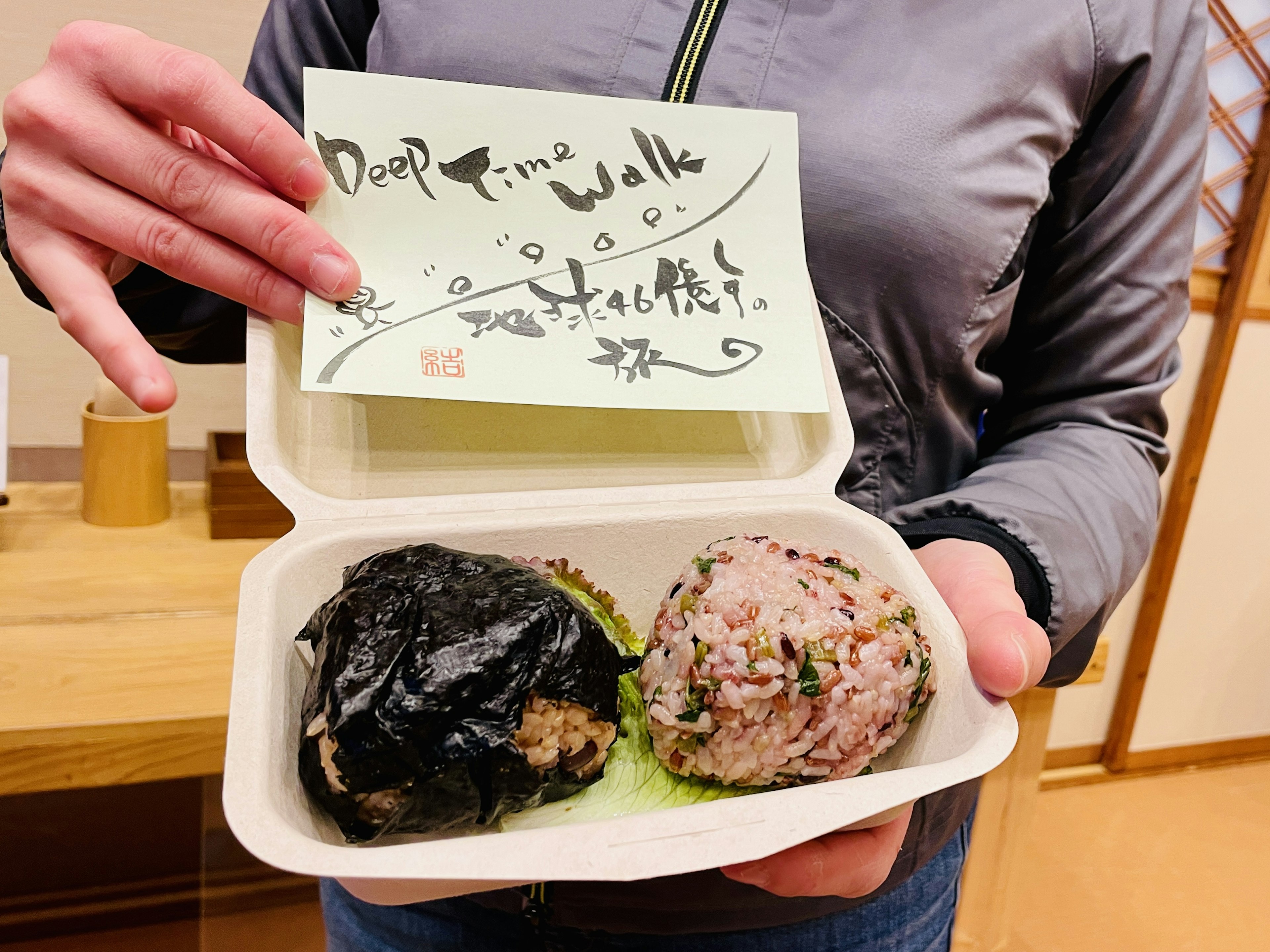 Person holding two rice balls with a note