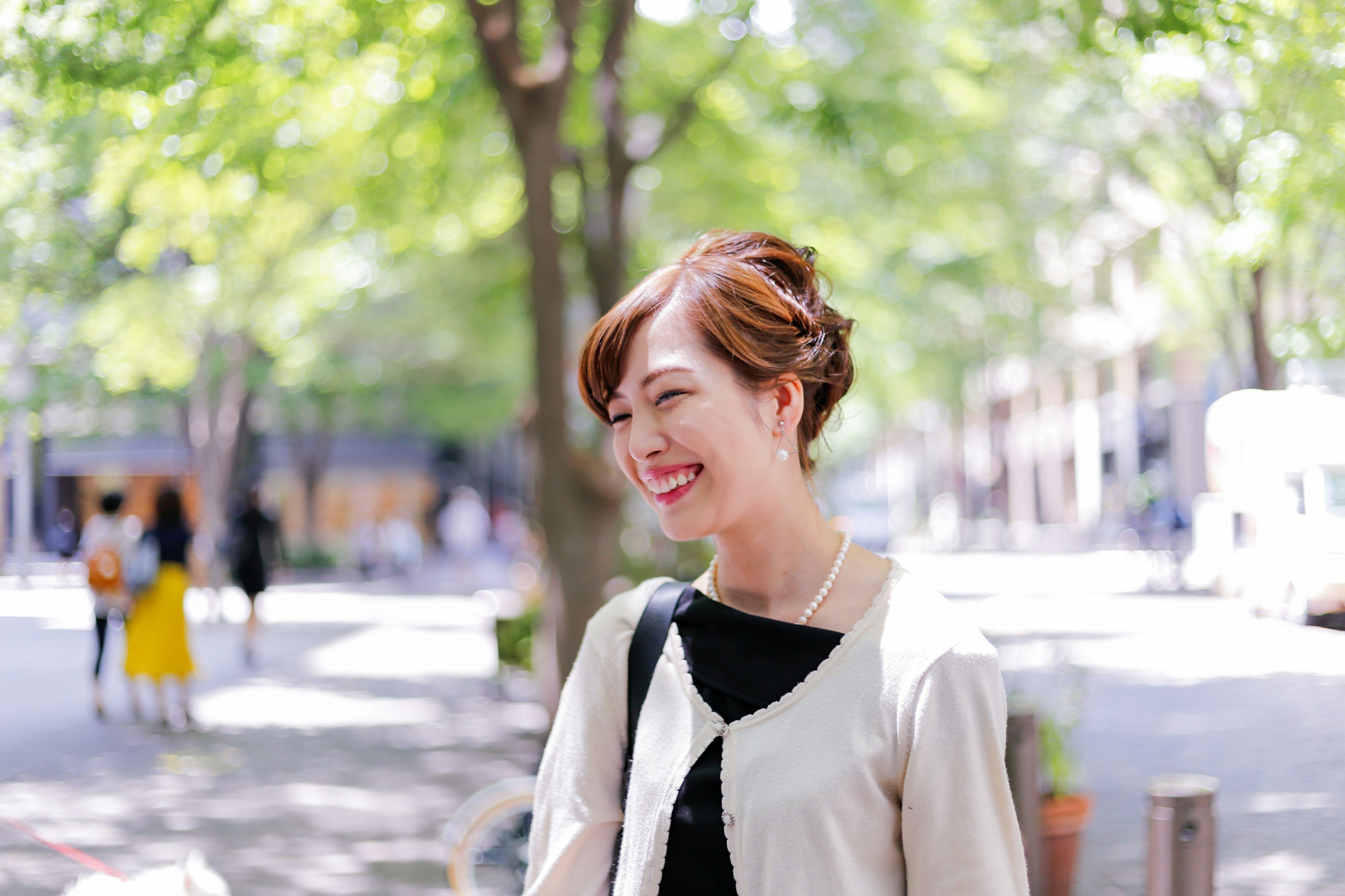 Portrait of a smiling woman in a park with green trees in the background