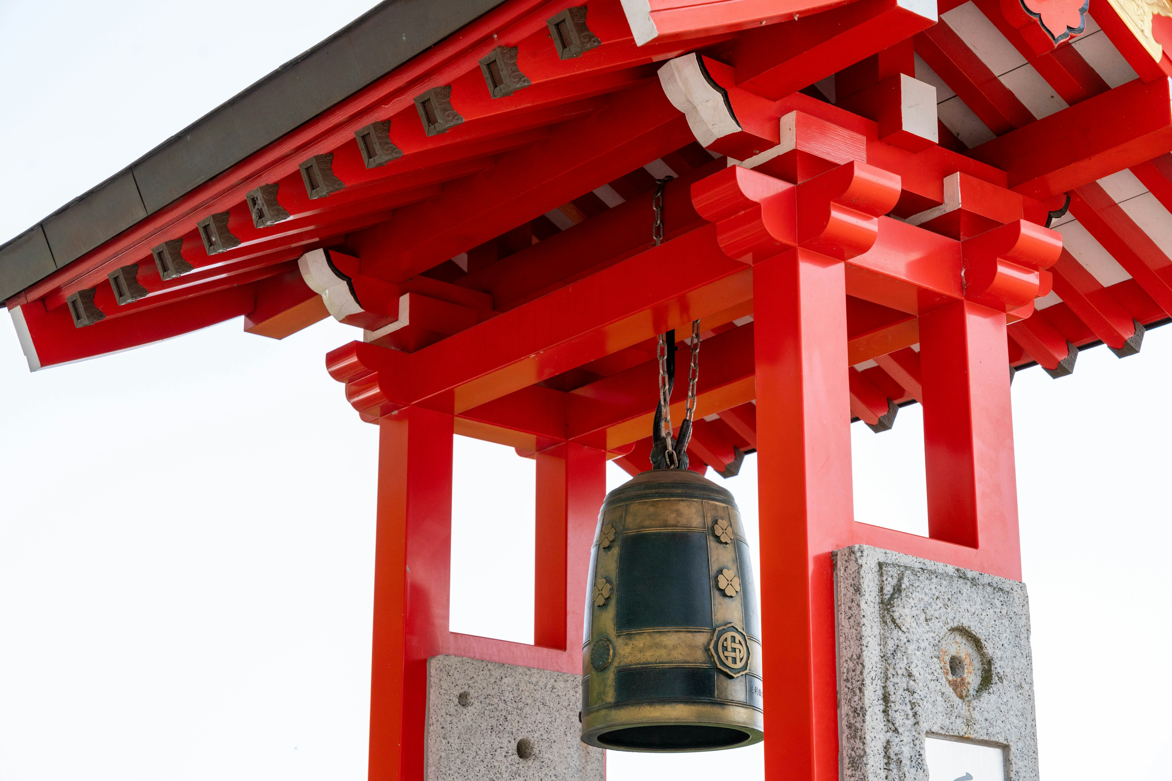 Image of a bell hanging under a red torii gate