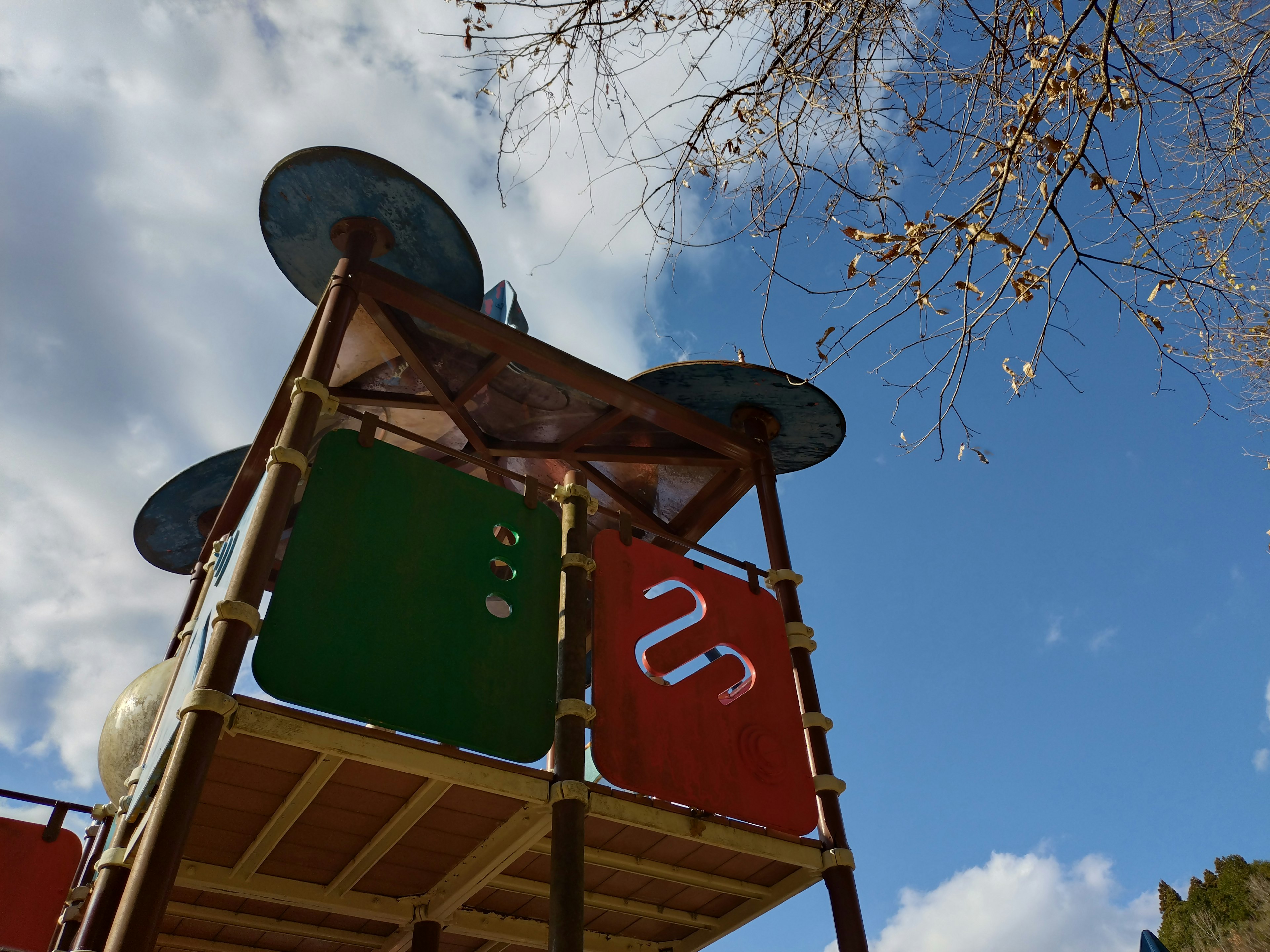 Bunte Spielstruktur mit grünen und orangefarbenen Platten vor blauem Himmel