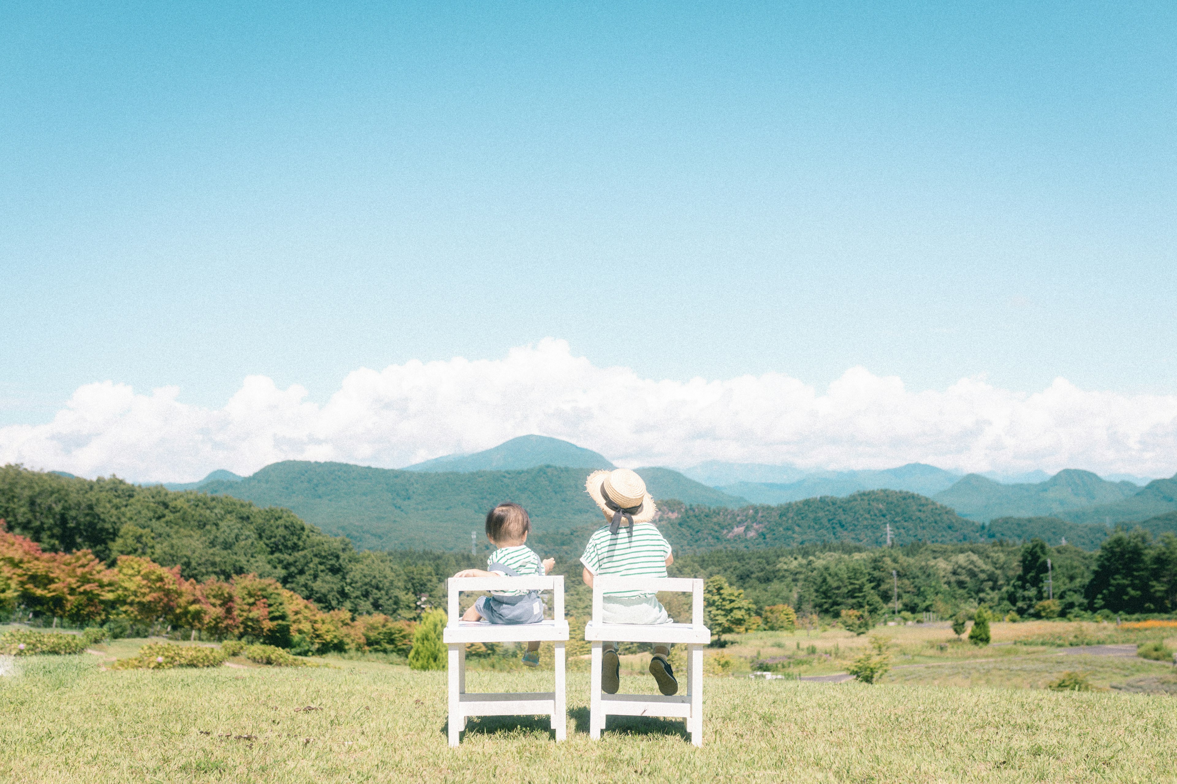 Dos personas sentadas en sillas blancas mirando montañas y un cielo azul claro