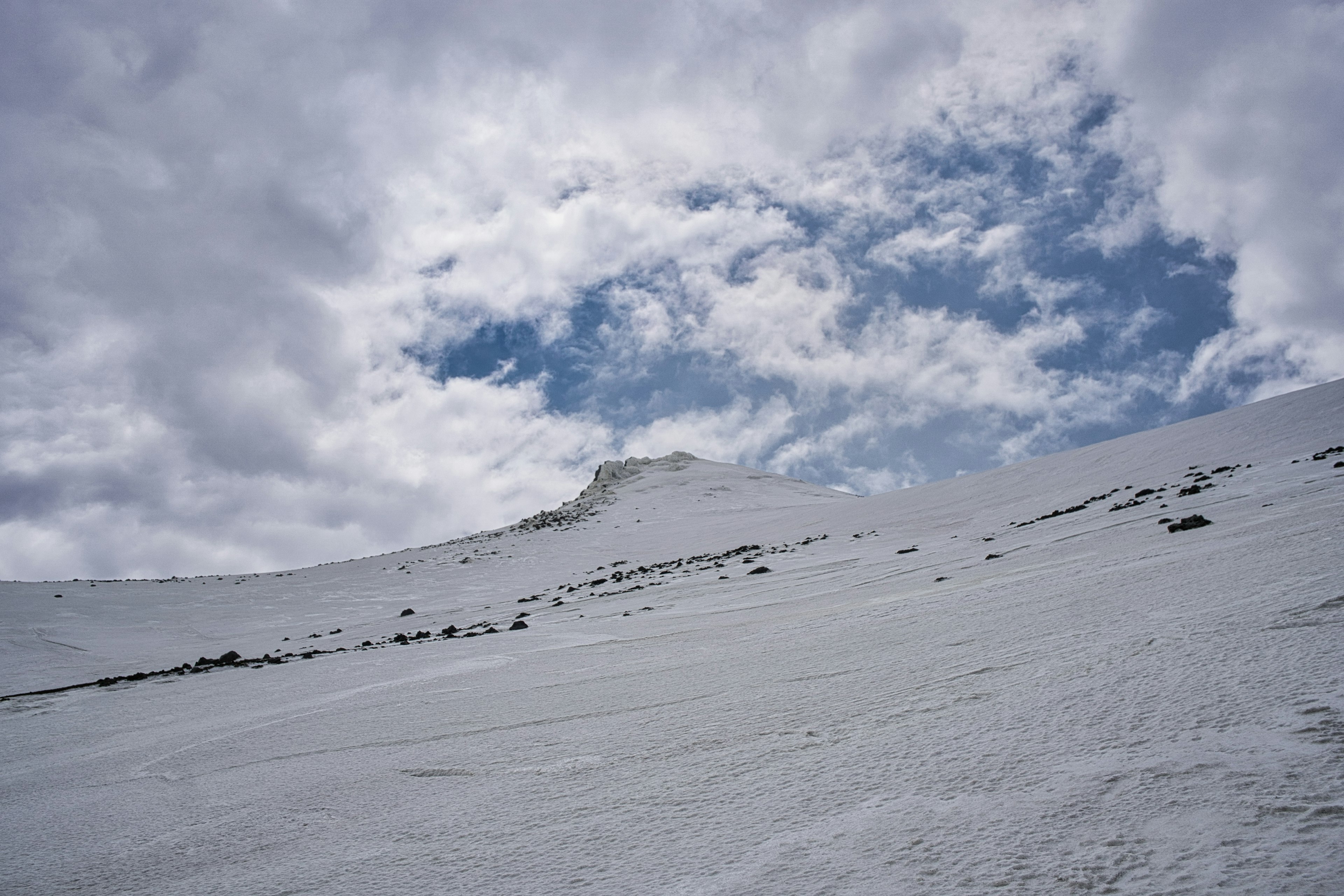 Schneebedeckte Bergseite mit blauem Himmel und Wolken