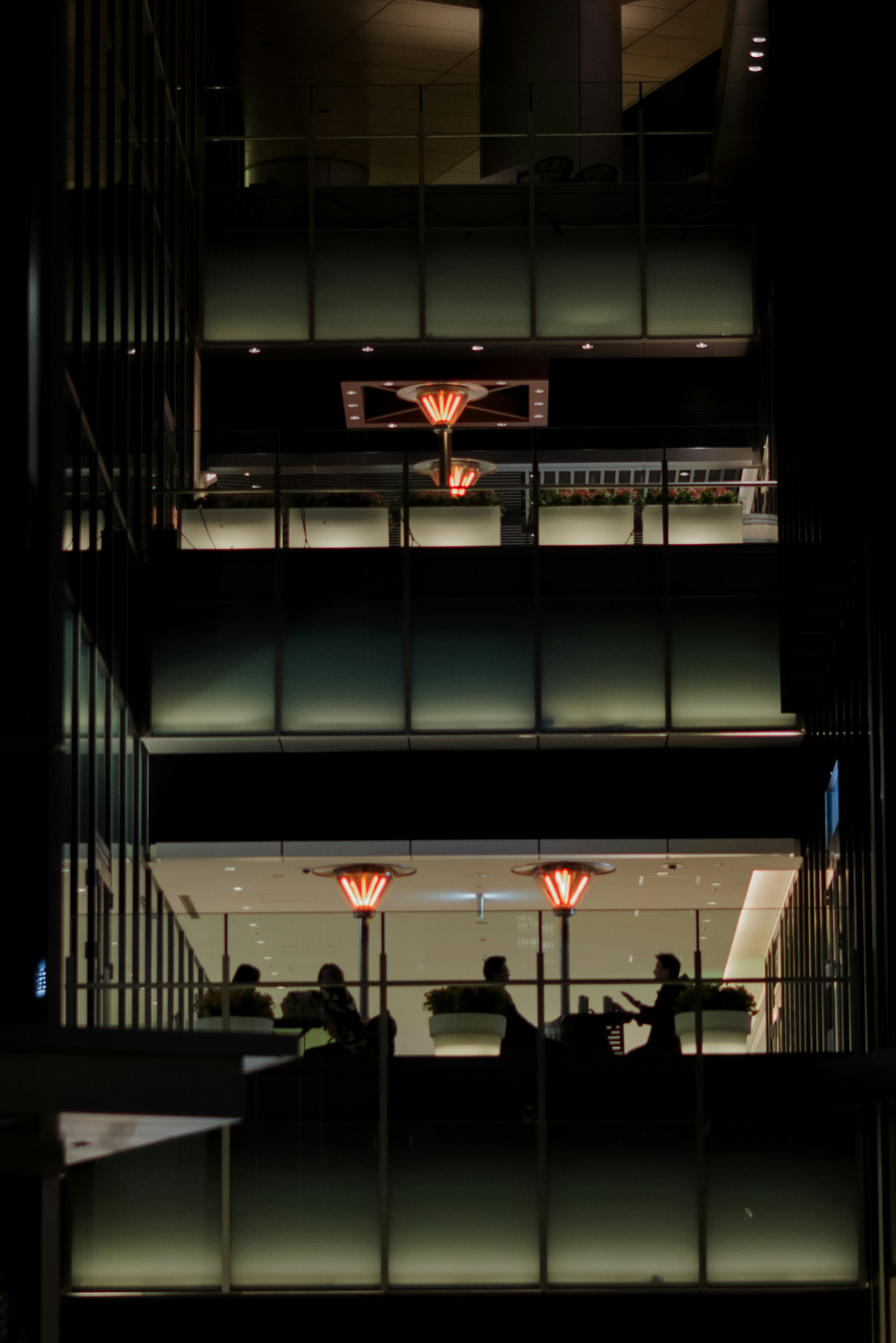 Escalier d'un bâtiment moderne avec des silhouettes de personnes sur fond sombre