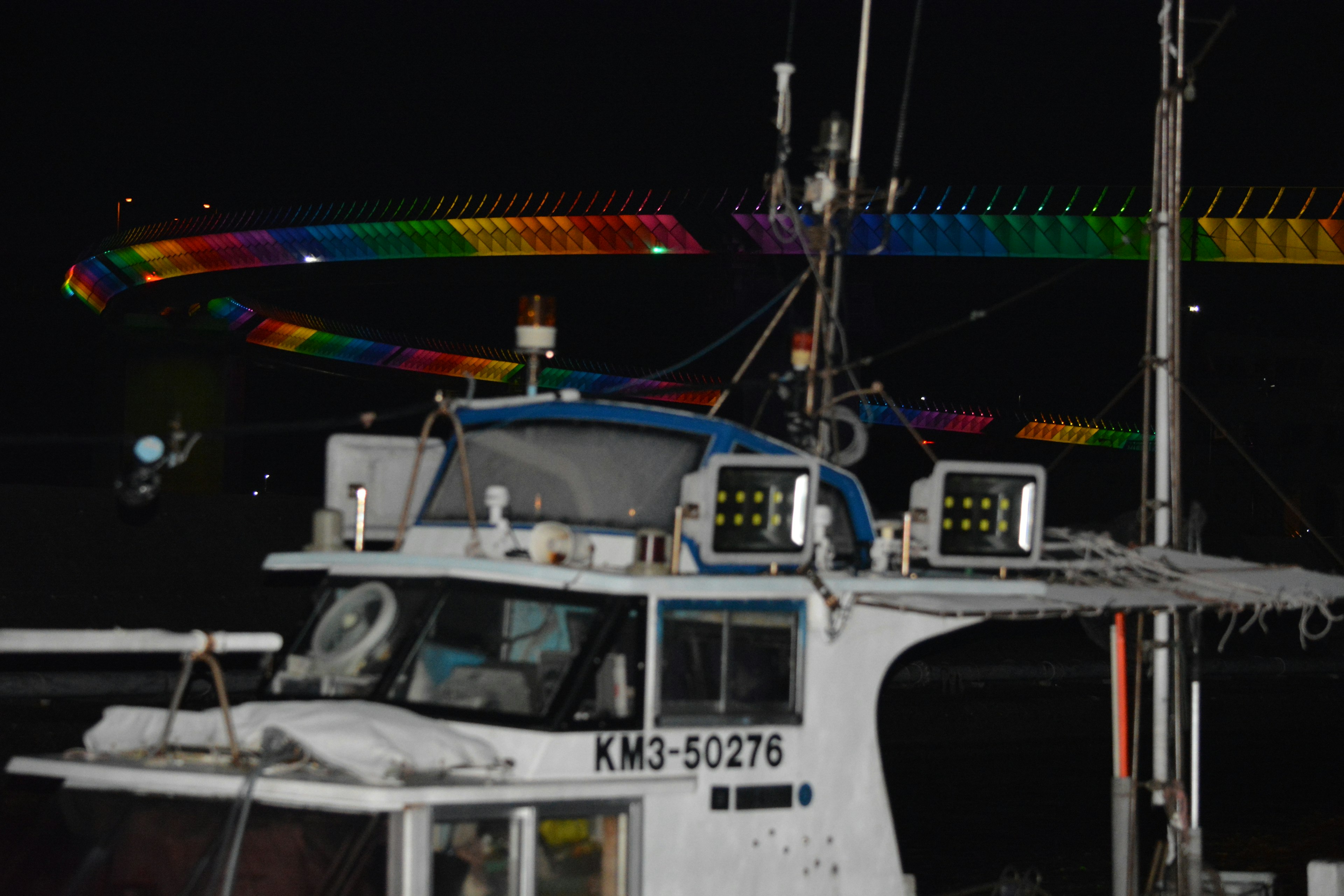 Fishing boat docked at night with colorful lights in the background