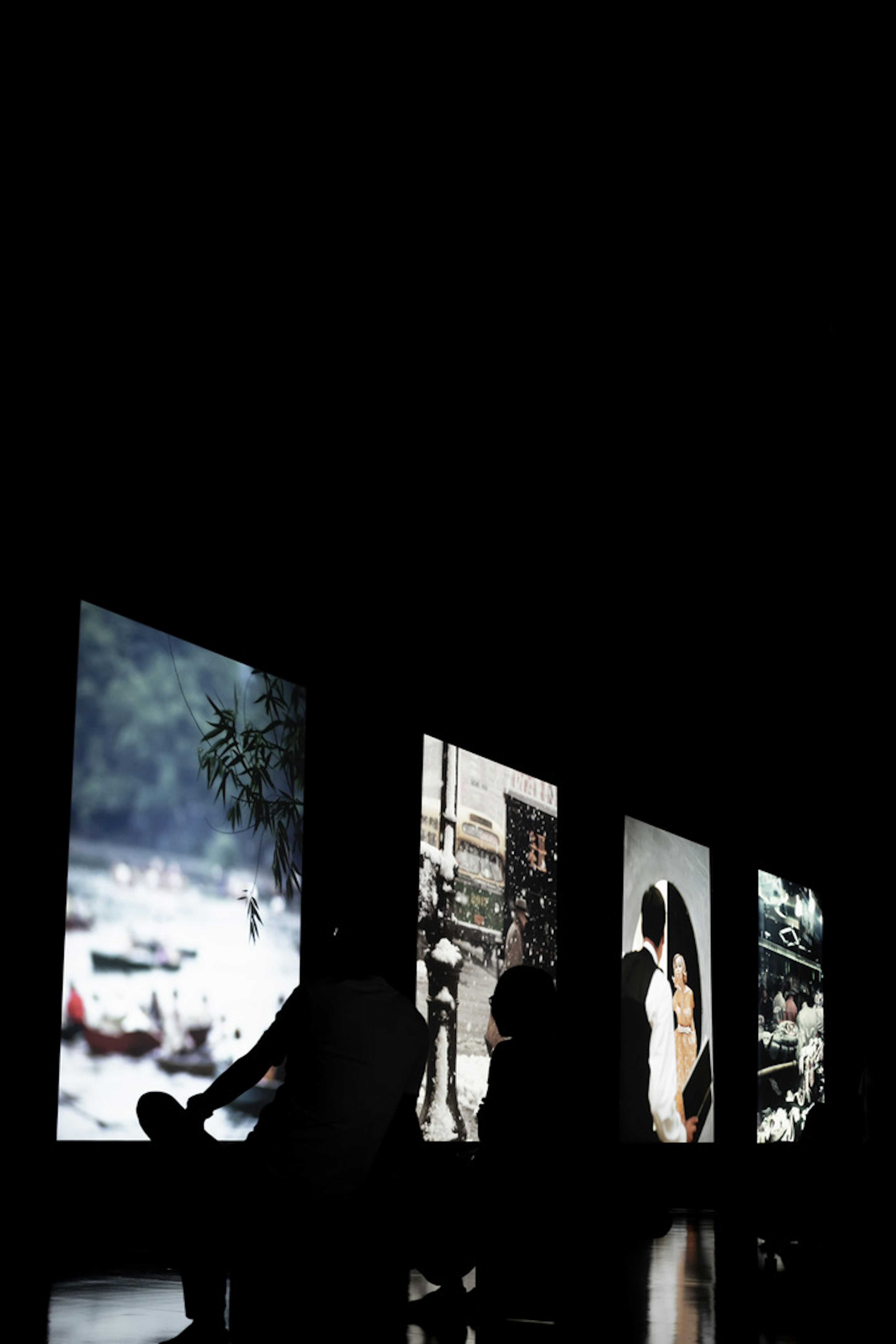 Silhouettes de personnes regardant des photographies projetées sur un fond sombre