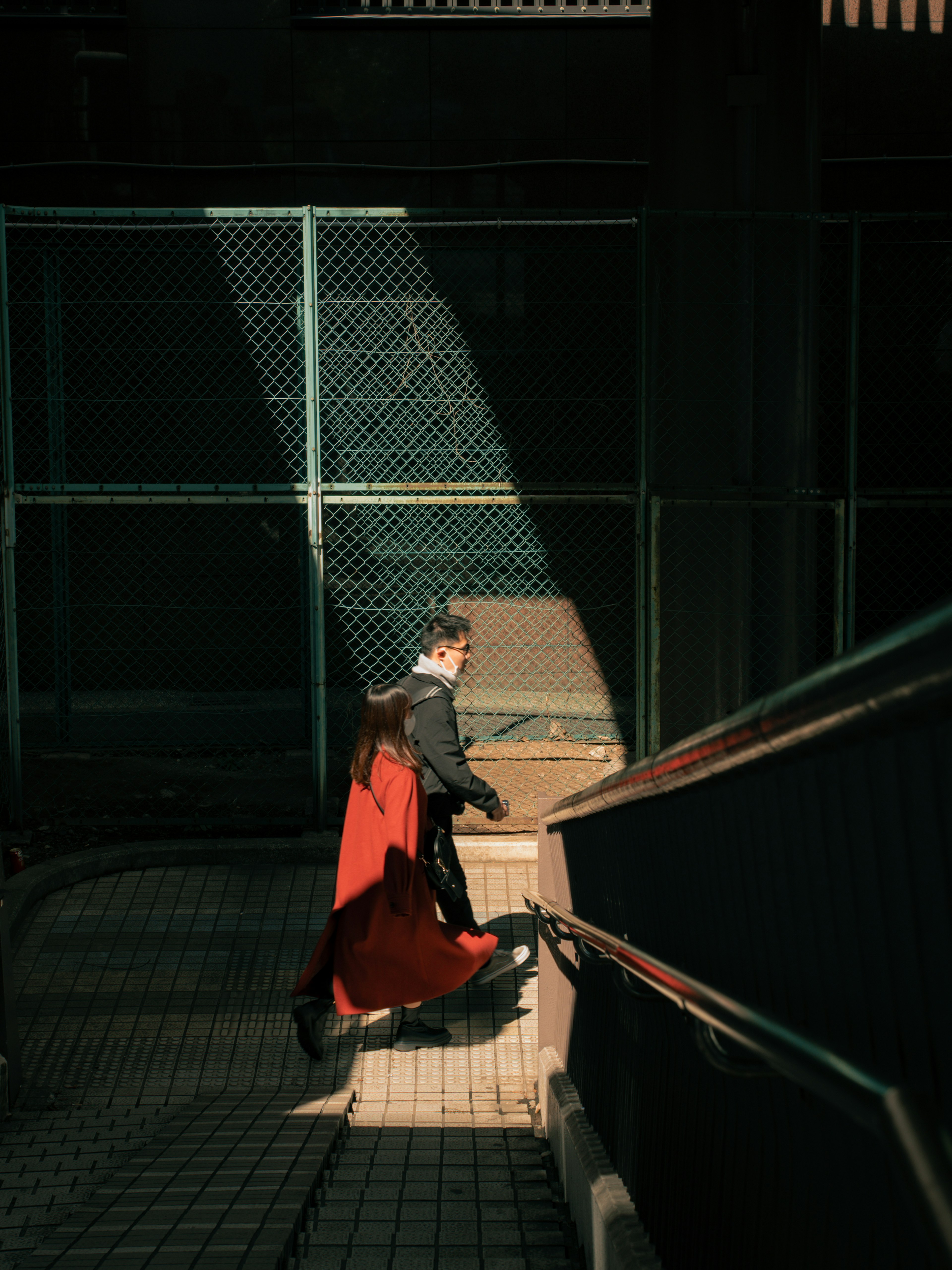 A person in a red coat walking up stairs Light and shadow contrast creates a dramatic effect