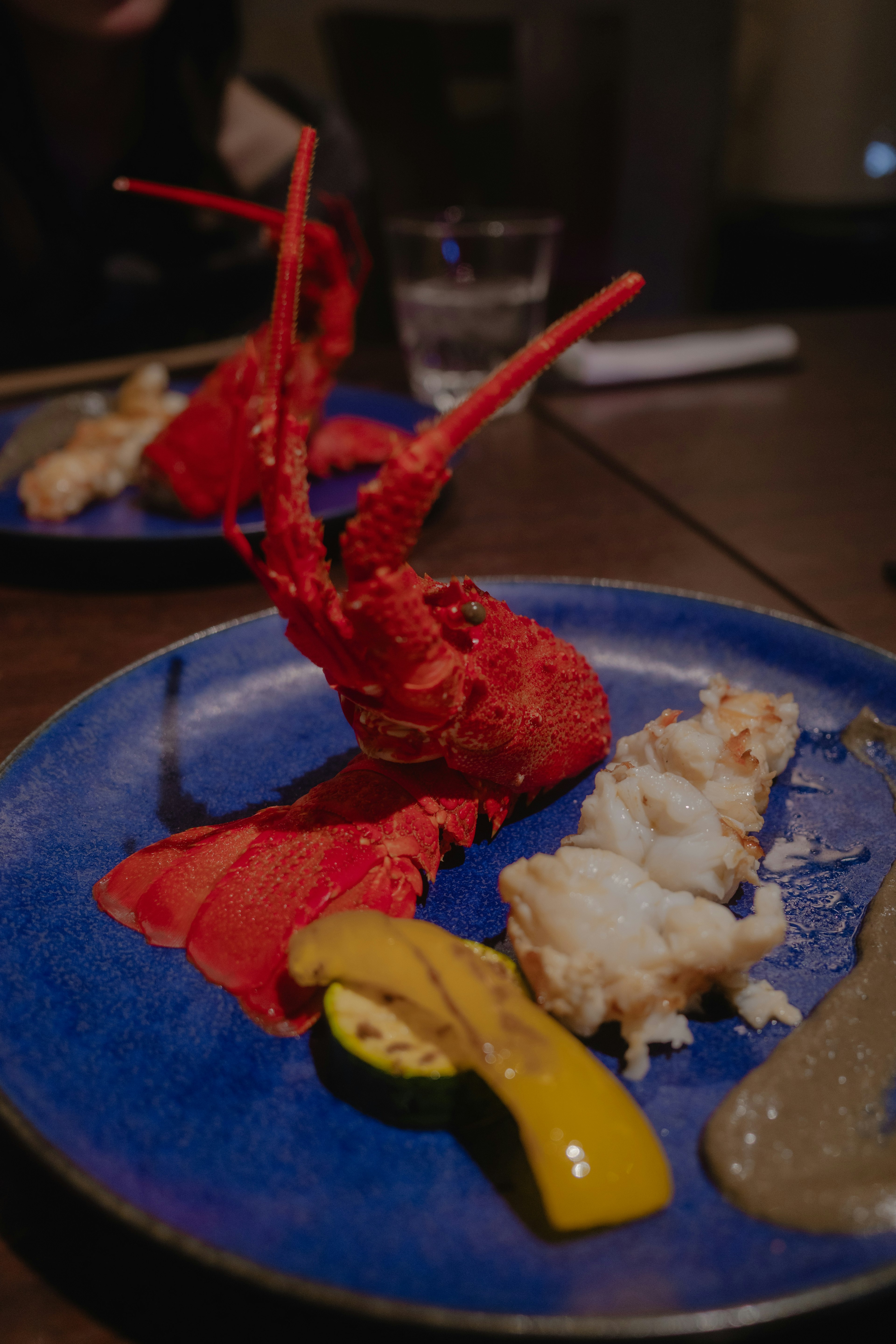 Un plat de homard vibrant sur une assiette bleue avec de la viande de homard garnie de côtés colorés