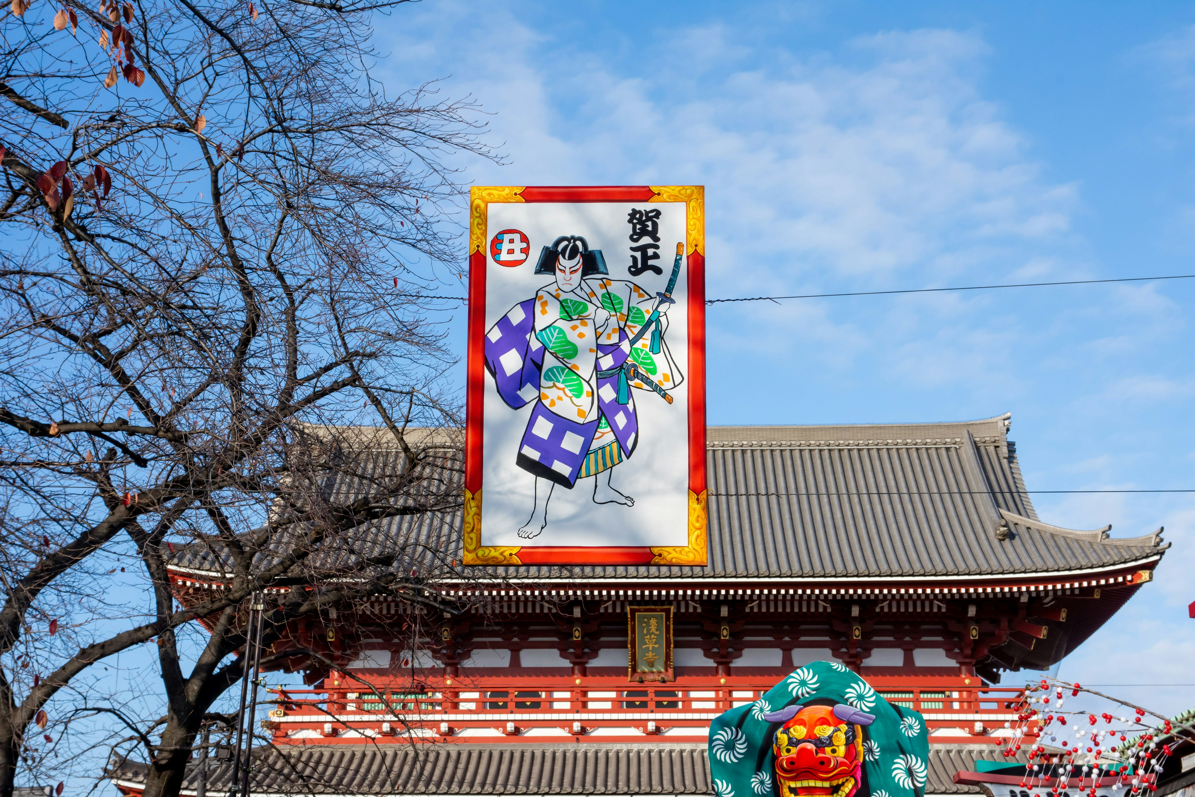 Banner colorido frente a un edificio japonés tradicional con ramas de árbol