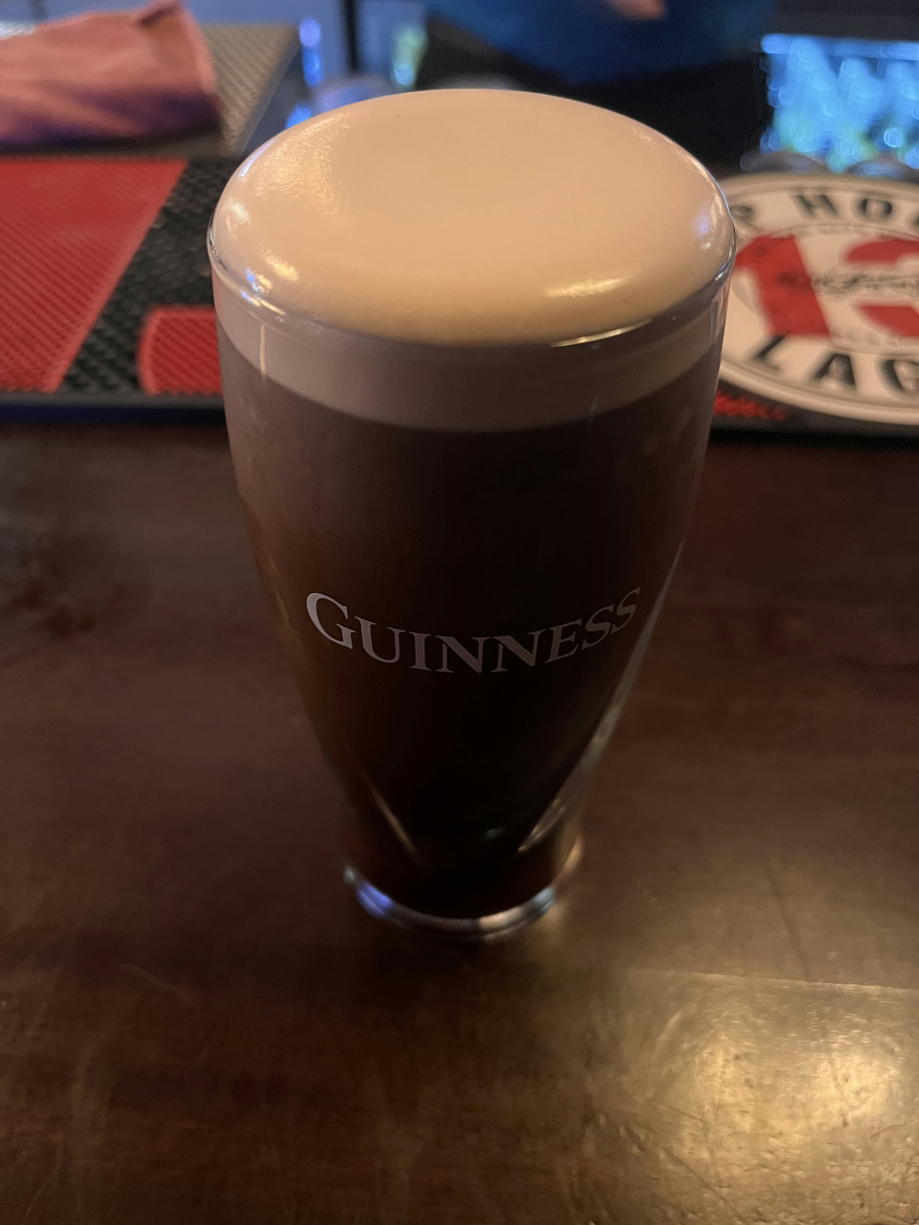 A glass of dark beer with a creamy foam on a wooden table