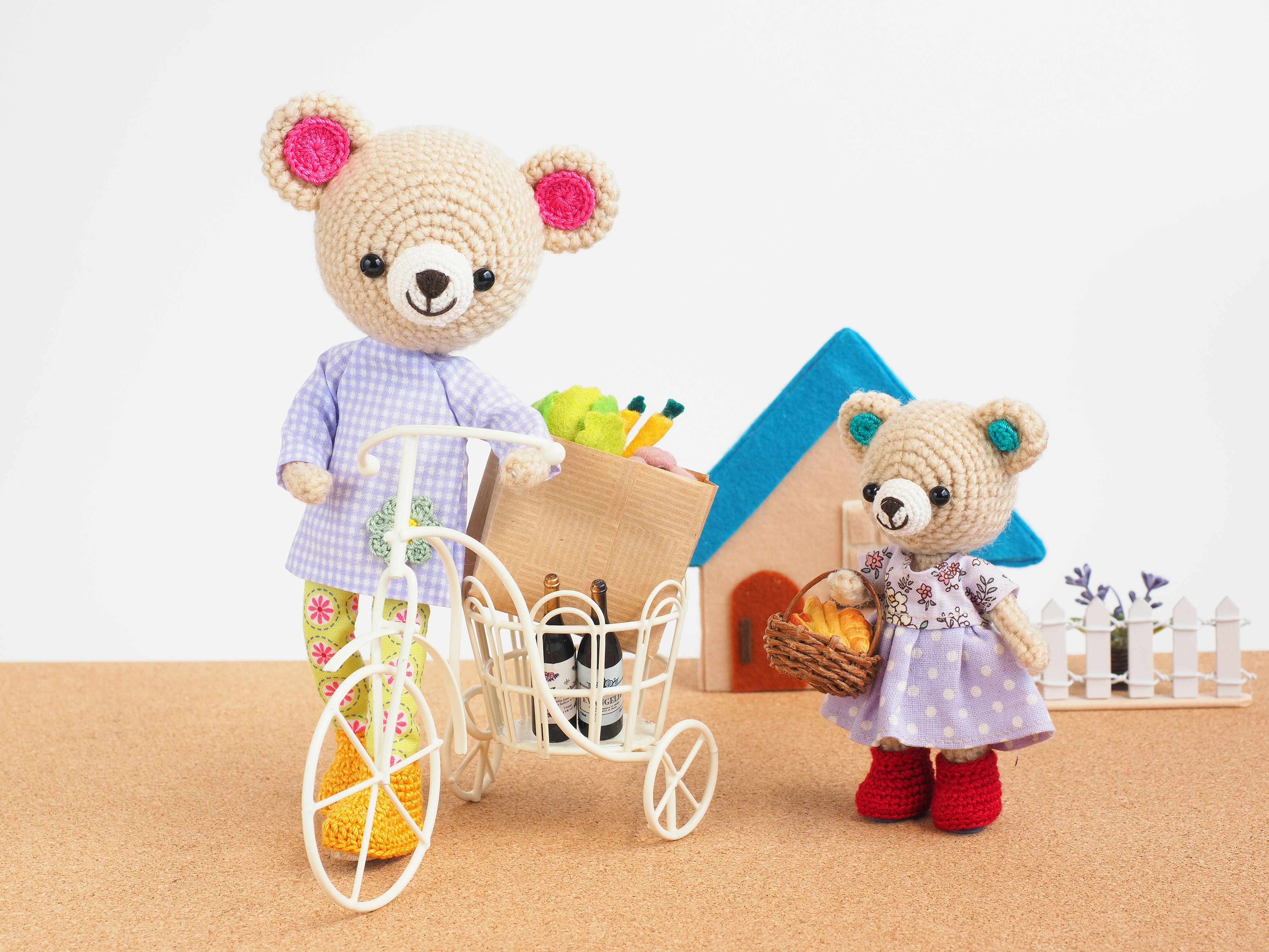 Colorful crochet bears with one on a bicycle and another holding a basket