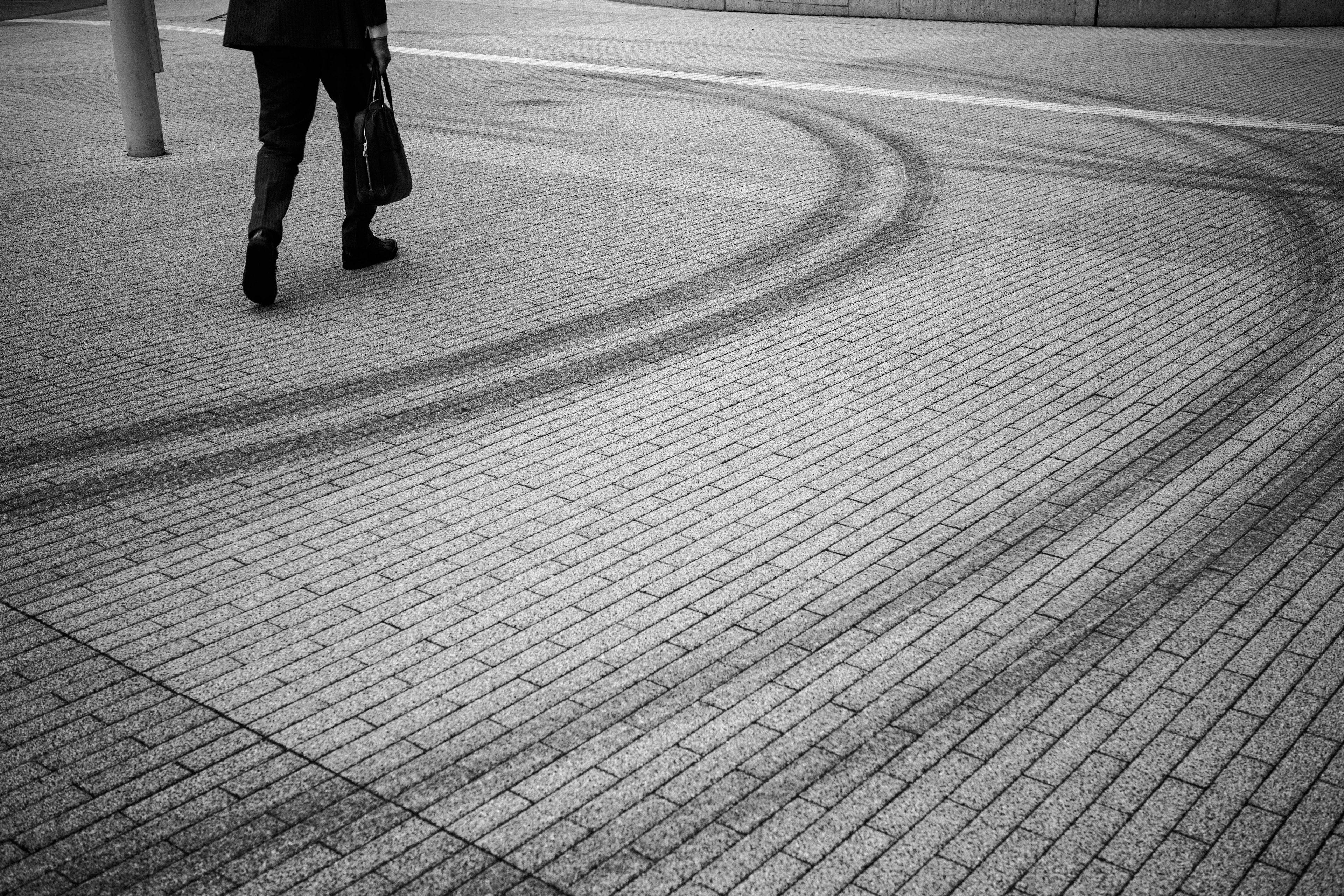 Une personne marchant sur une zone pavée avec des traces de pneus