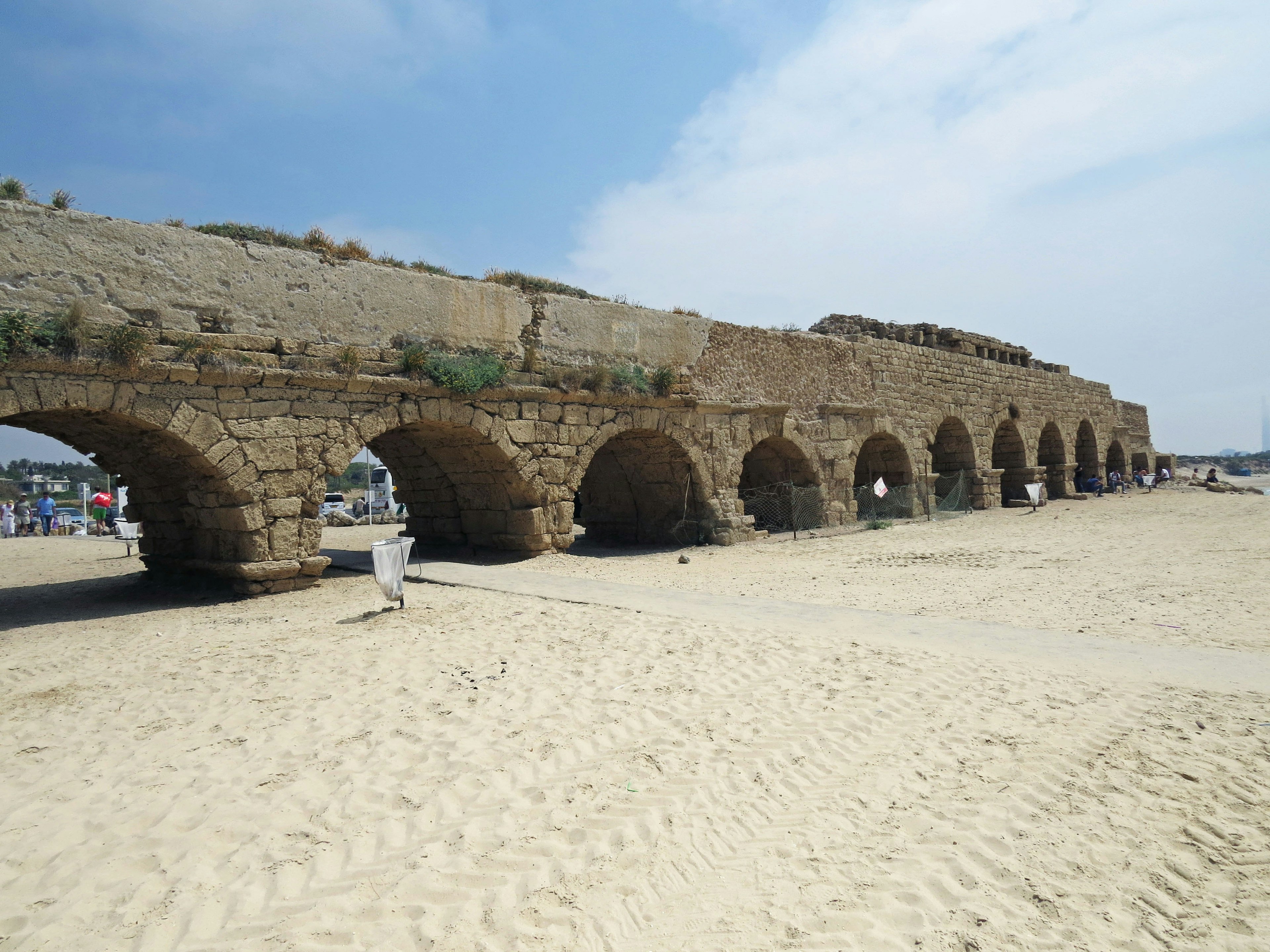 Ancient stone aqueduct arches on sandy beach