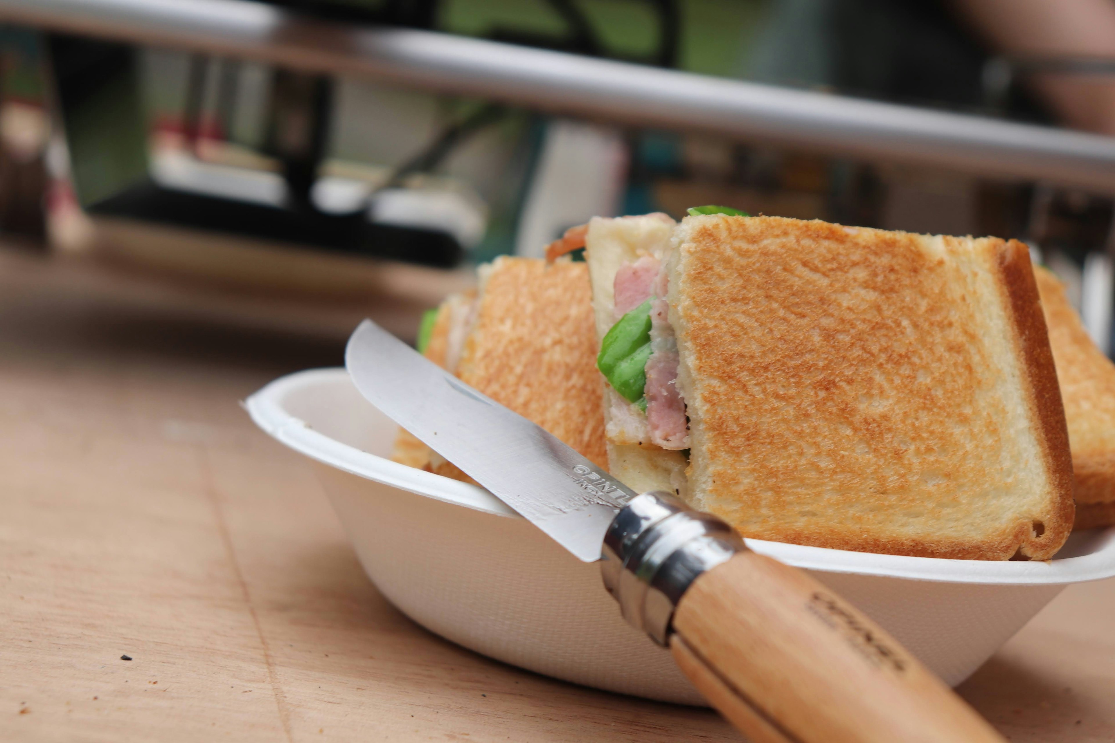 Sandwich on a plate with a wooden knife beside it