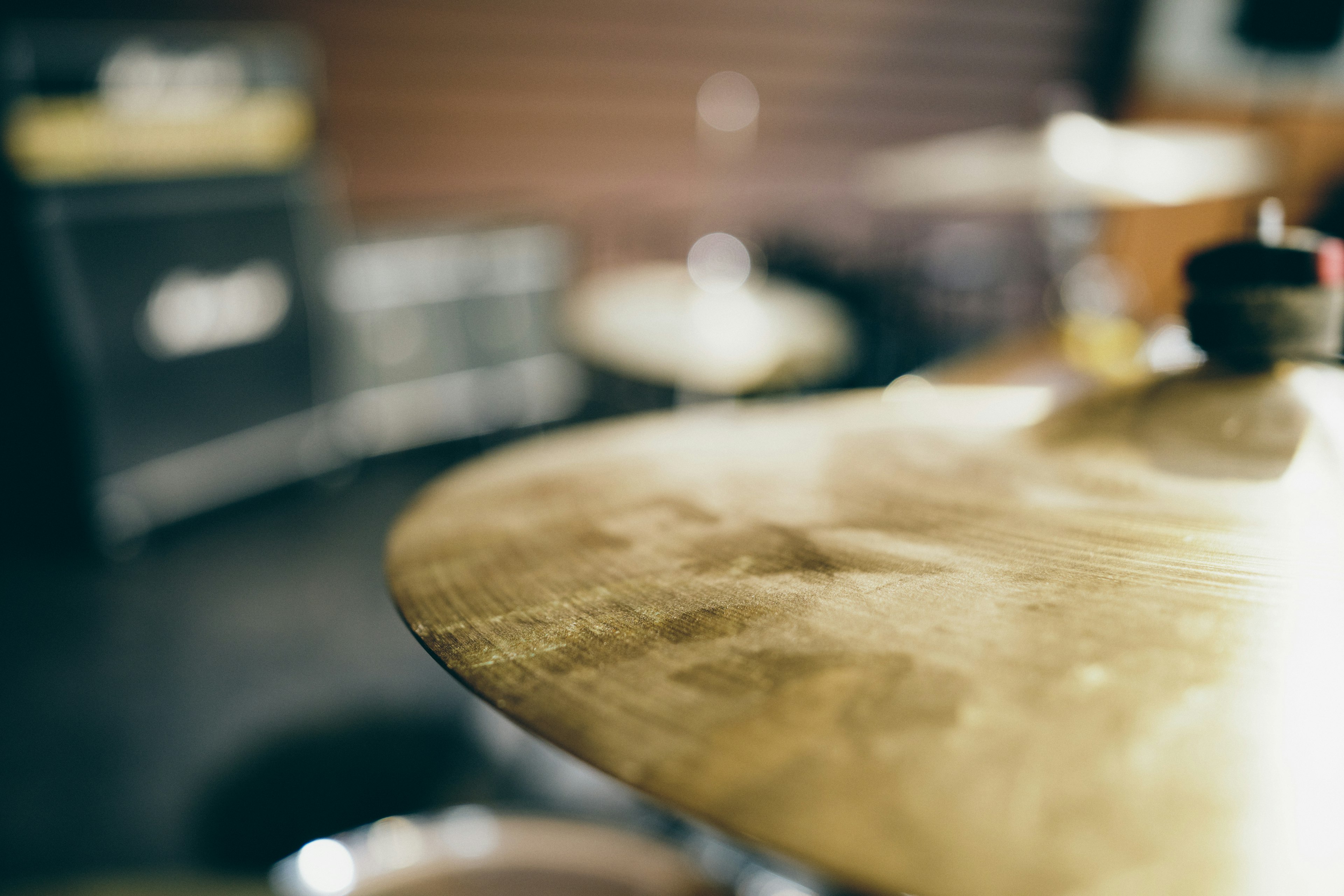 Close-up of a drum cymbal with an amplifier in the background