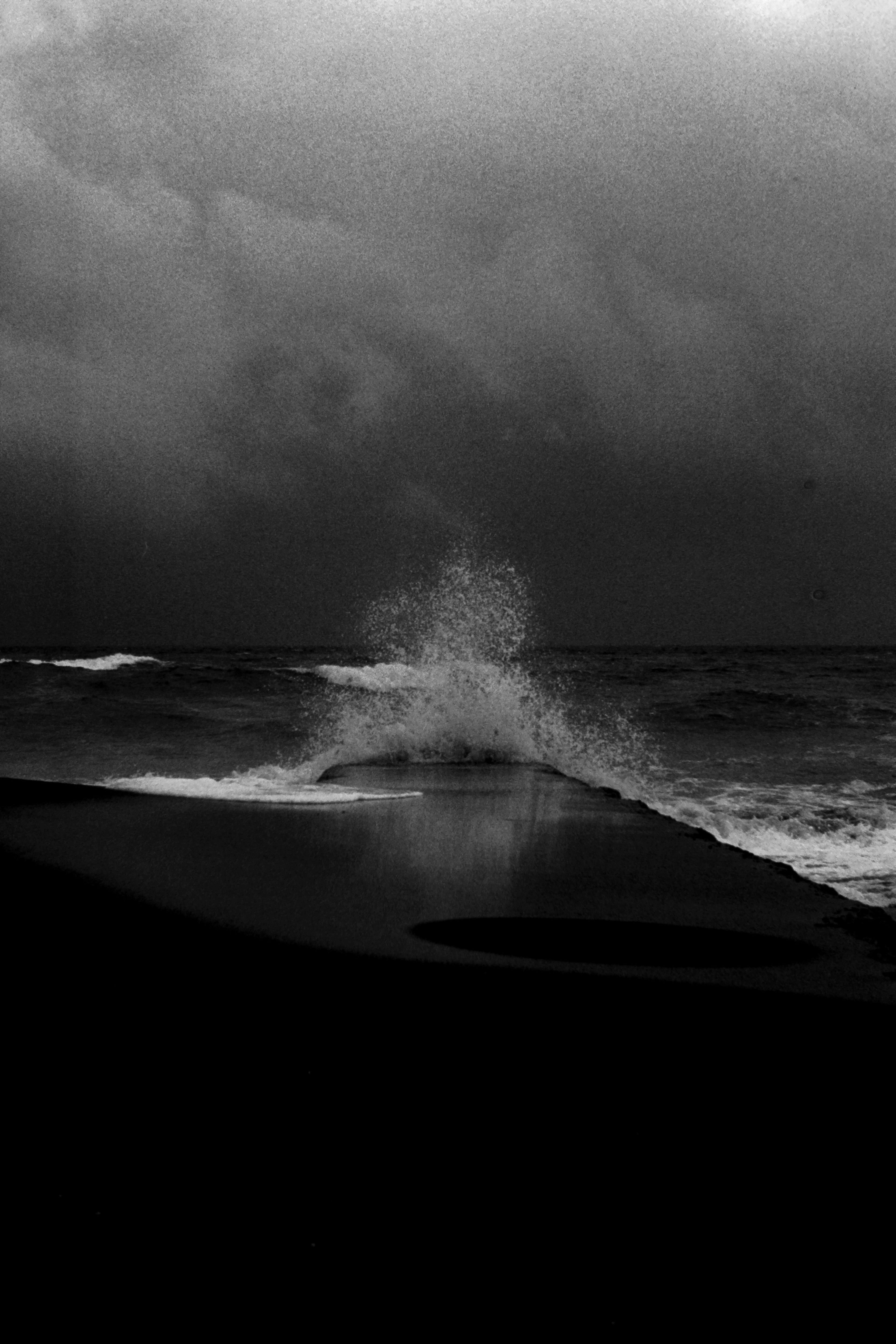 波浪在暴風雲下撞擊黑暗的海岸線