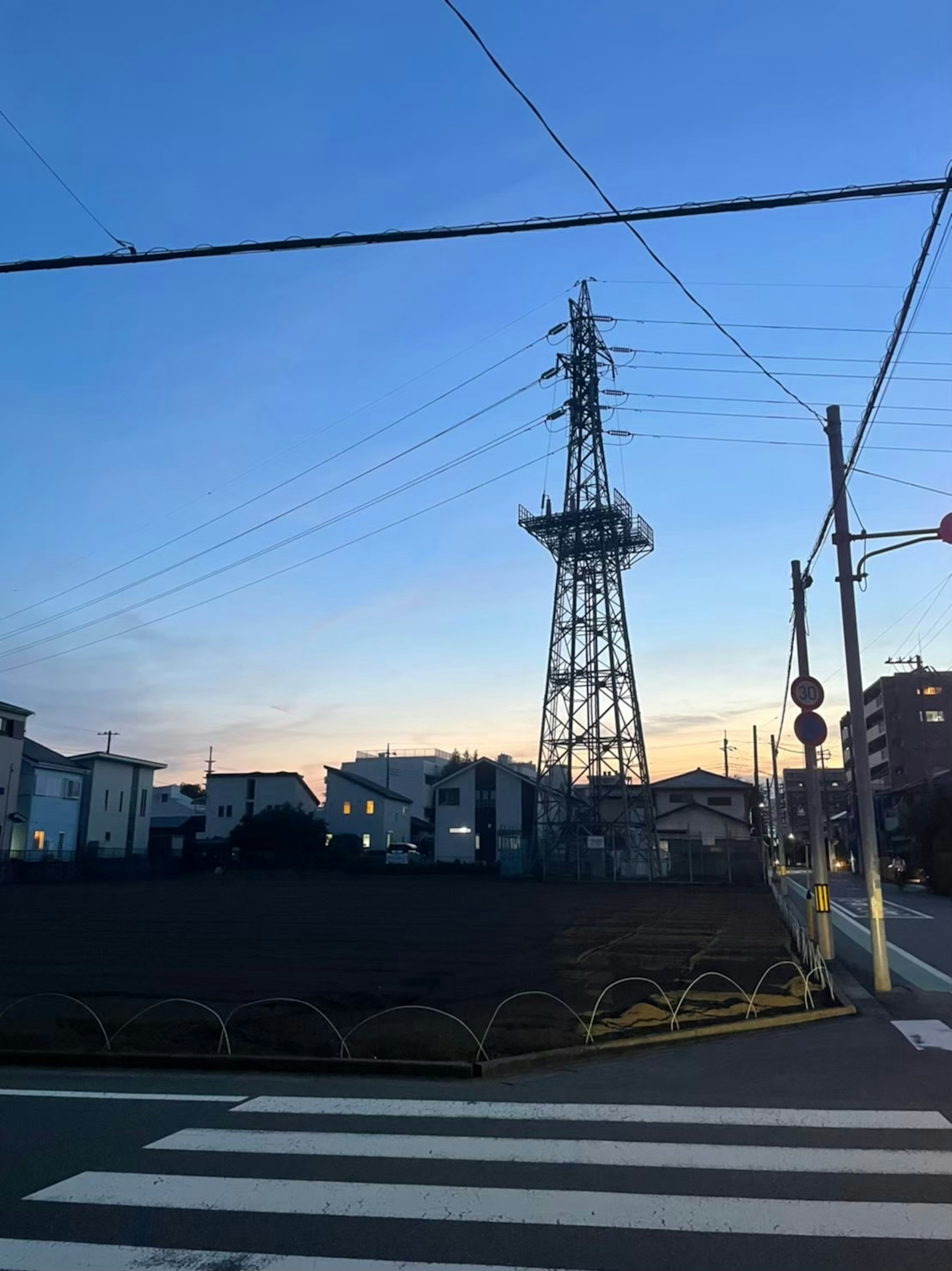 Una torre radiofonica si erge contro un cielo blu con un'area residenziale