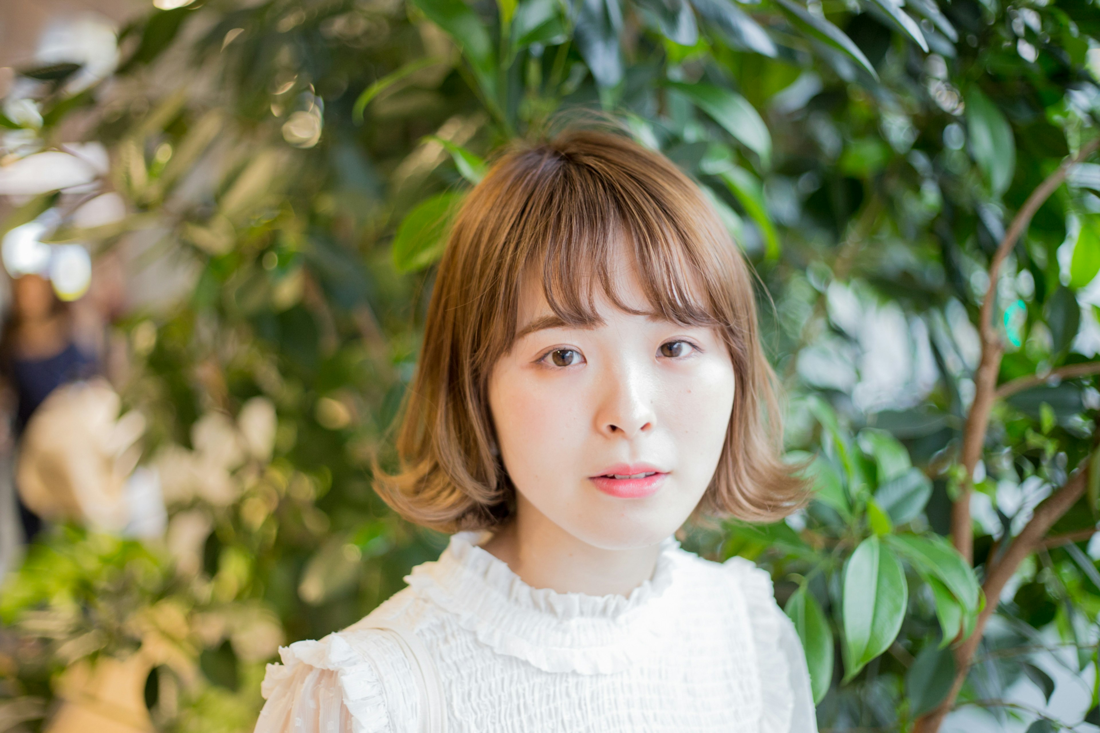 Retrato de una mujer con cabello corto frente a plantas verdes