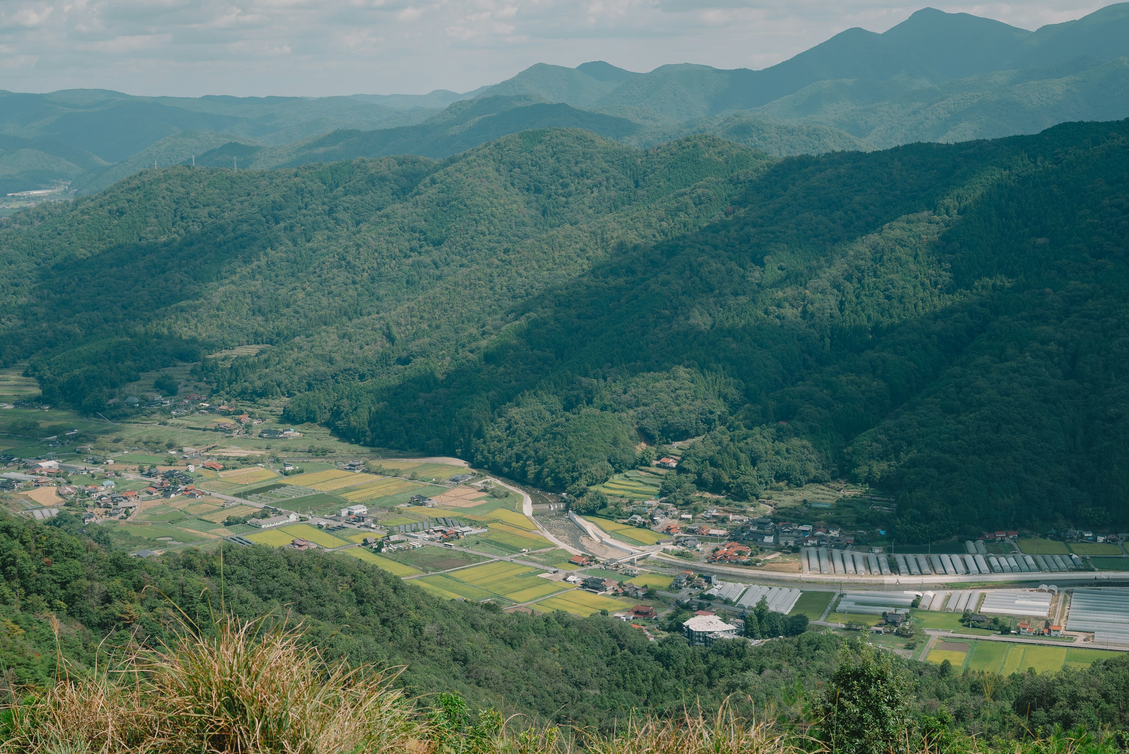 緑豊かな山々と谷間に広がる田園風景のパノラマ