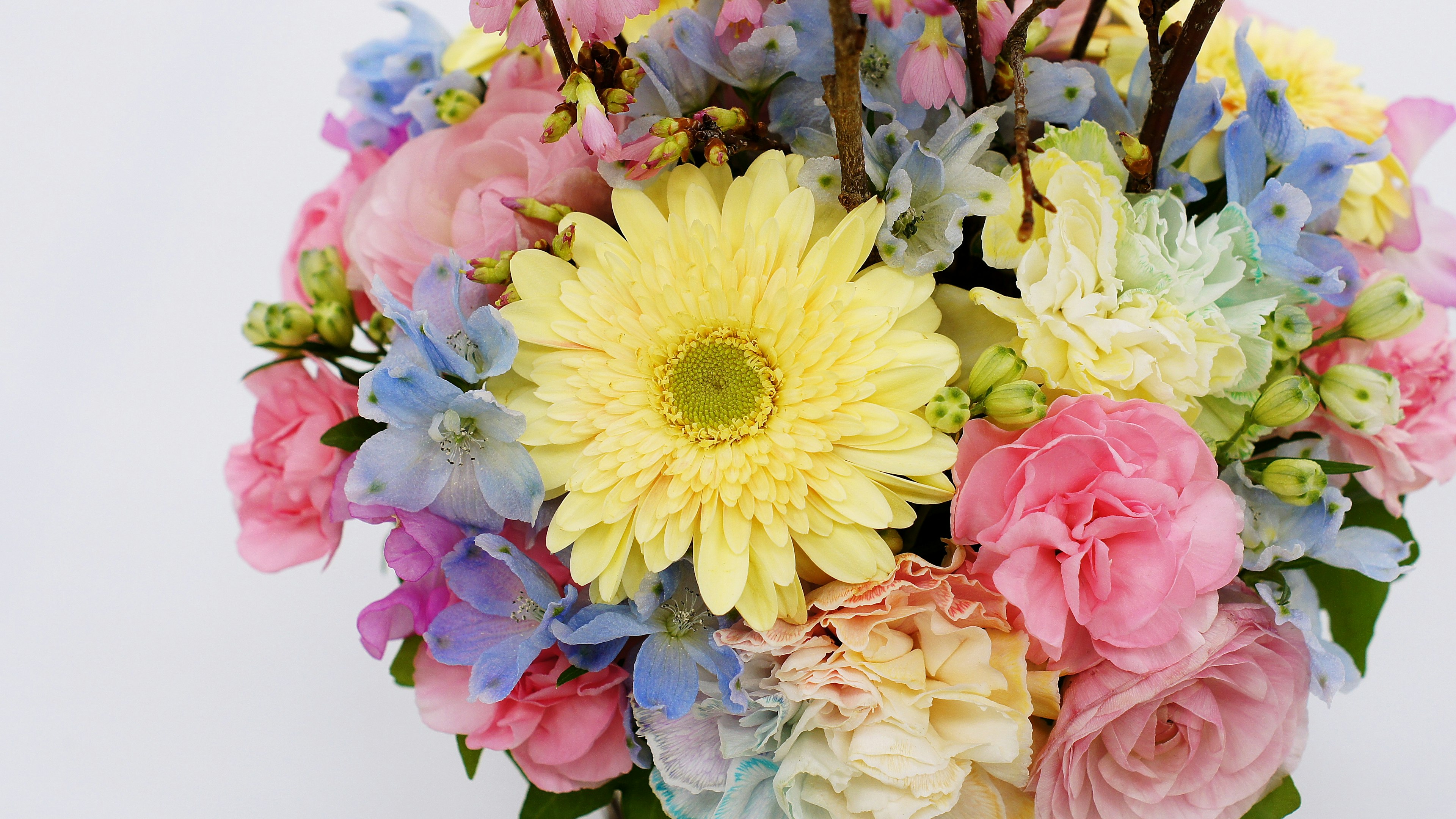 A vibrant bouquet of flowers featuring a yellow gerbera and pink roses