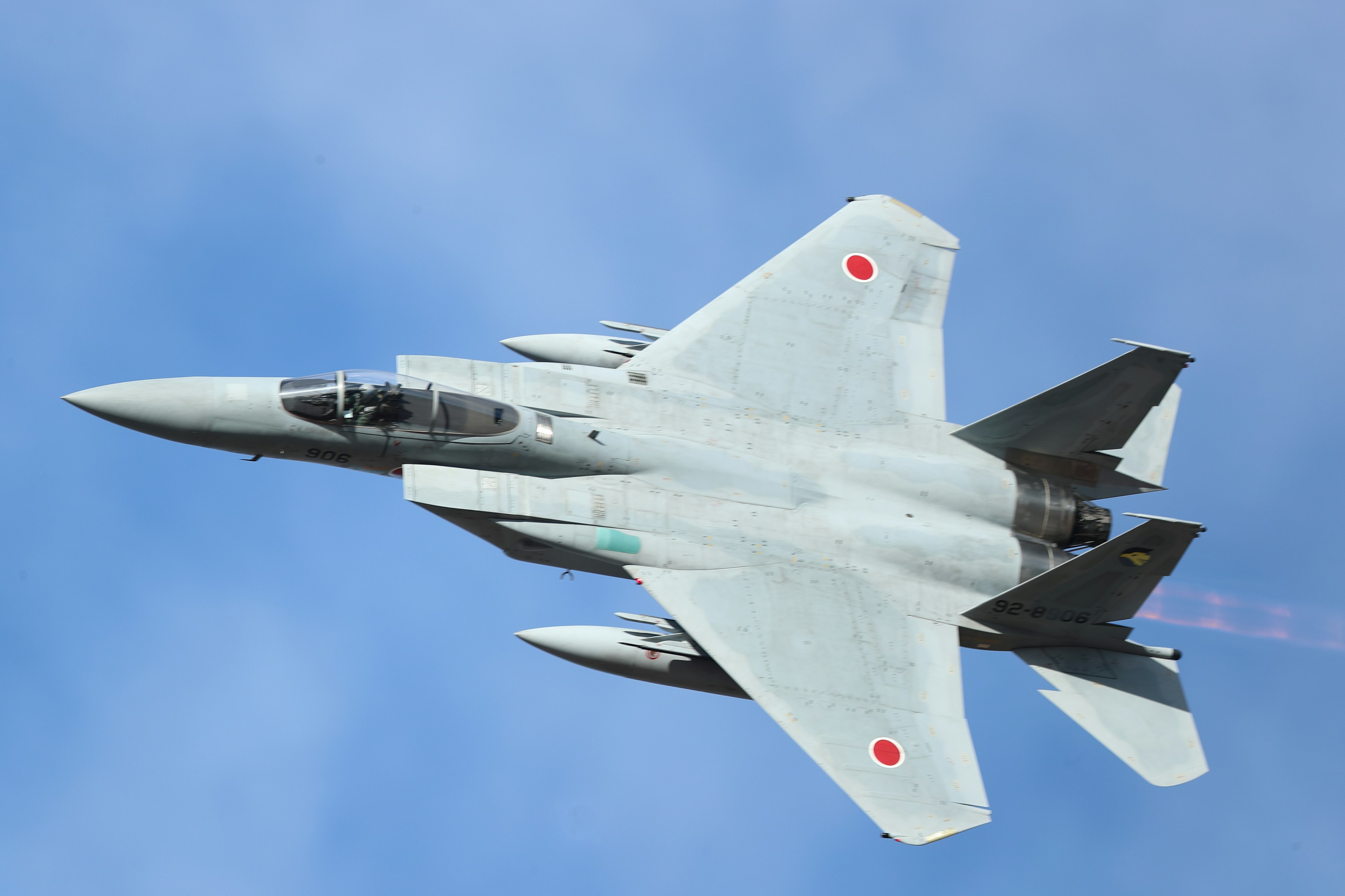 A white fighter jet flying in a blue sky