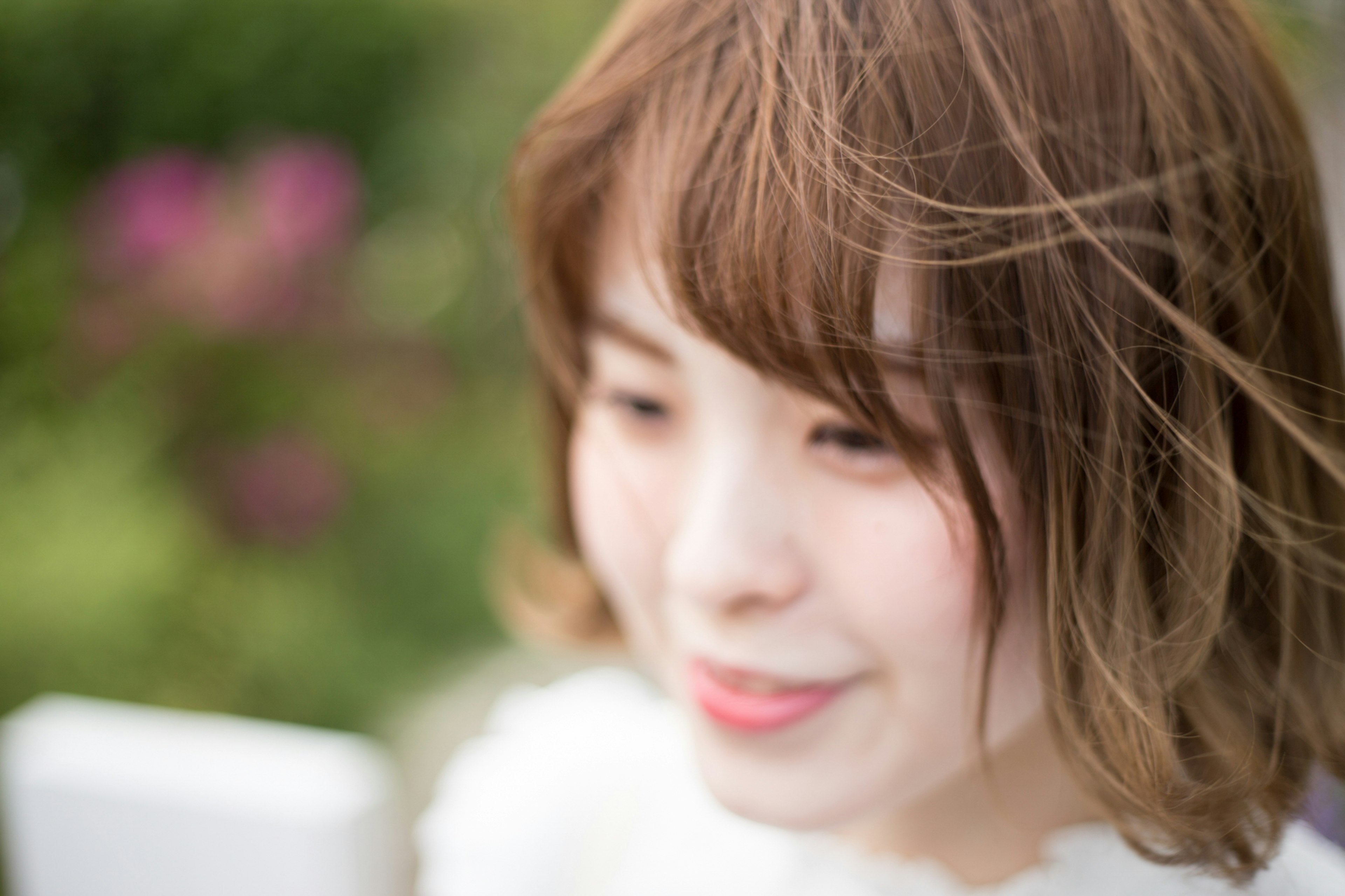 A young woman smiling outdoors with a soft background