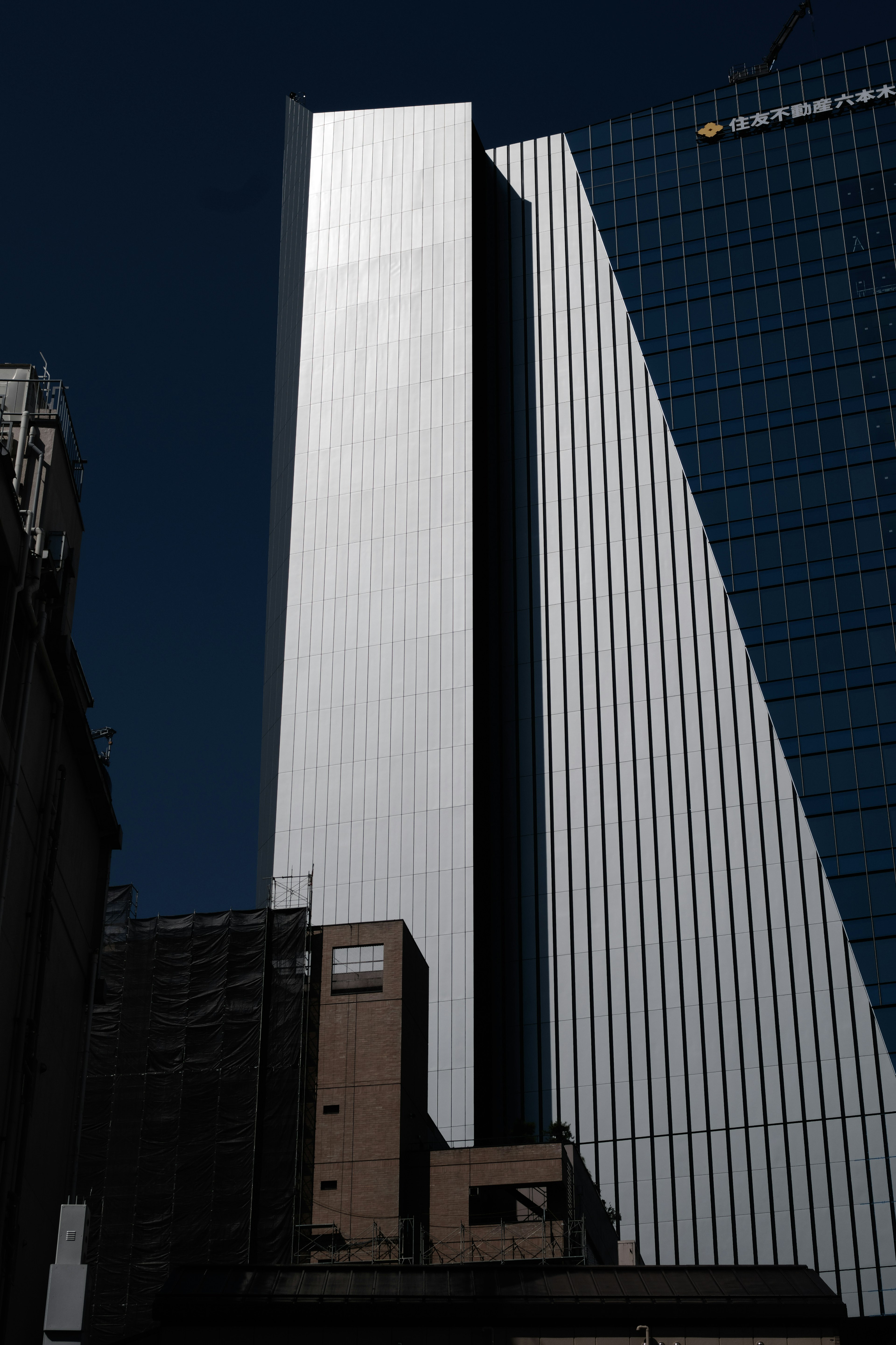 Nahaufnahme eines Wolkenkratzers mit metallischer Fassade und linarem Design vor einem dunklen Hintergrund