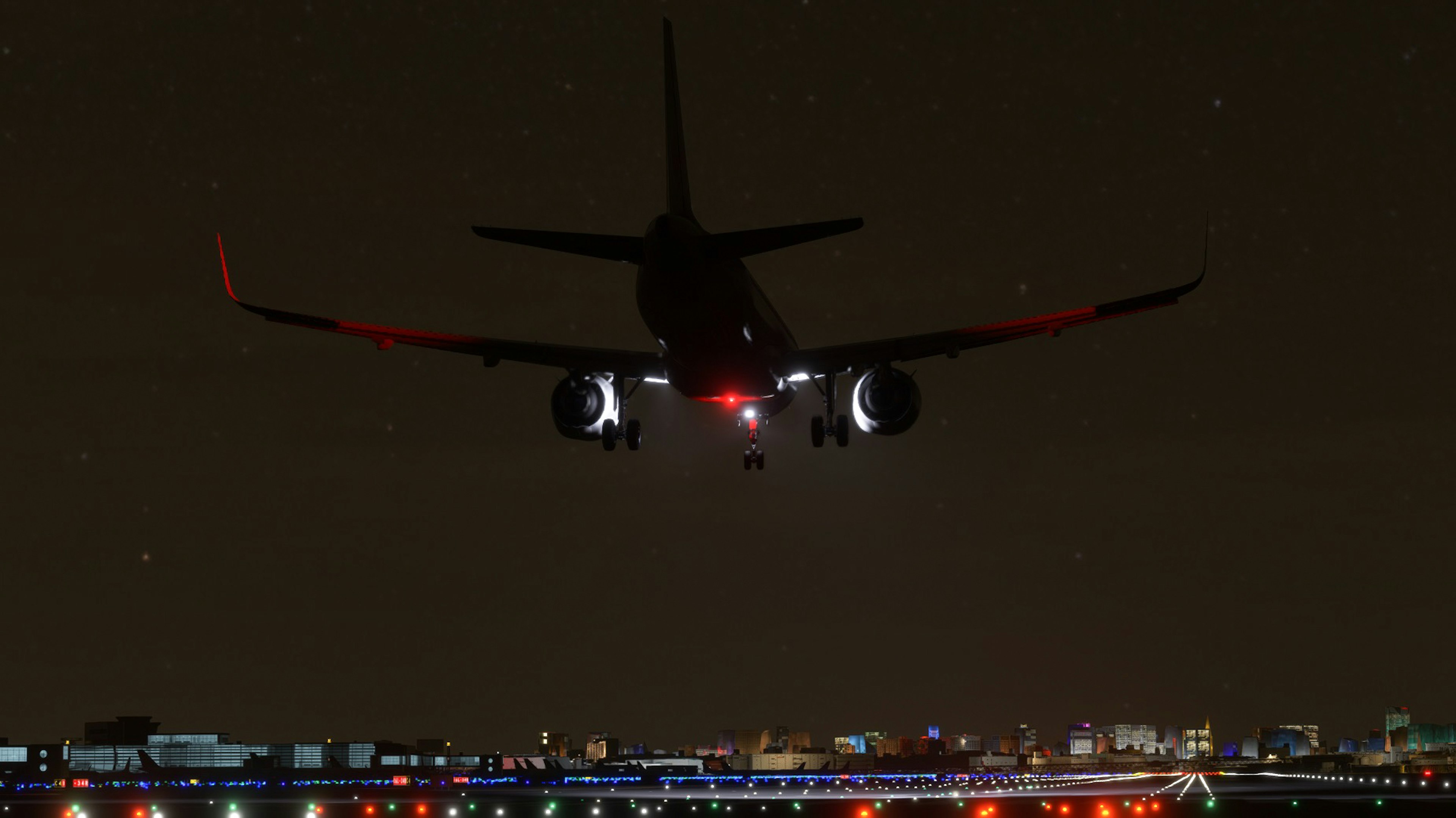 Silhouette of an airplane landing at night with bright city lights