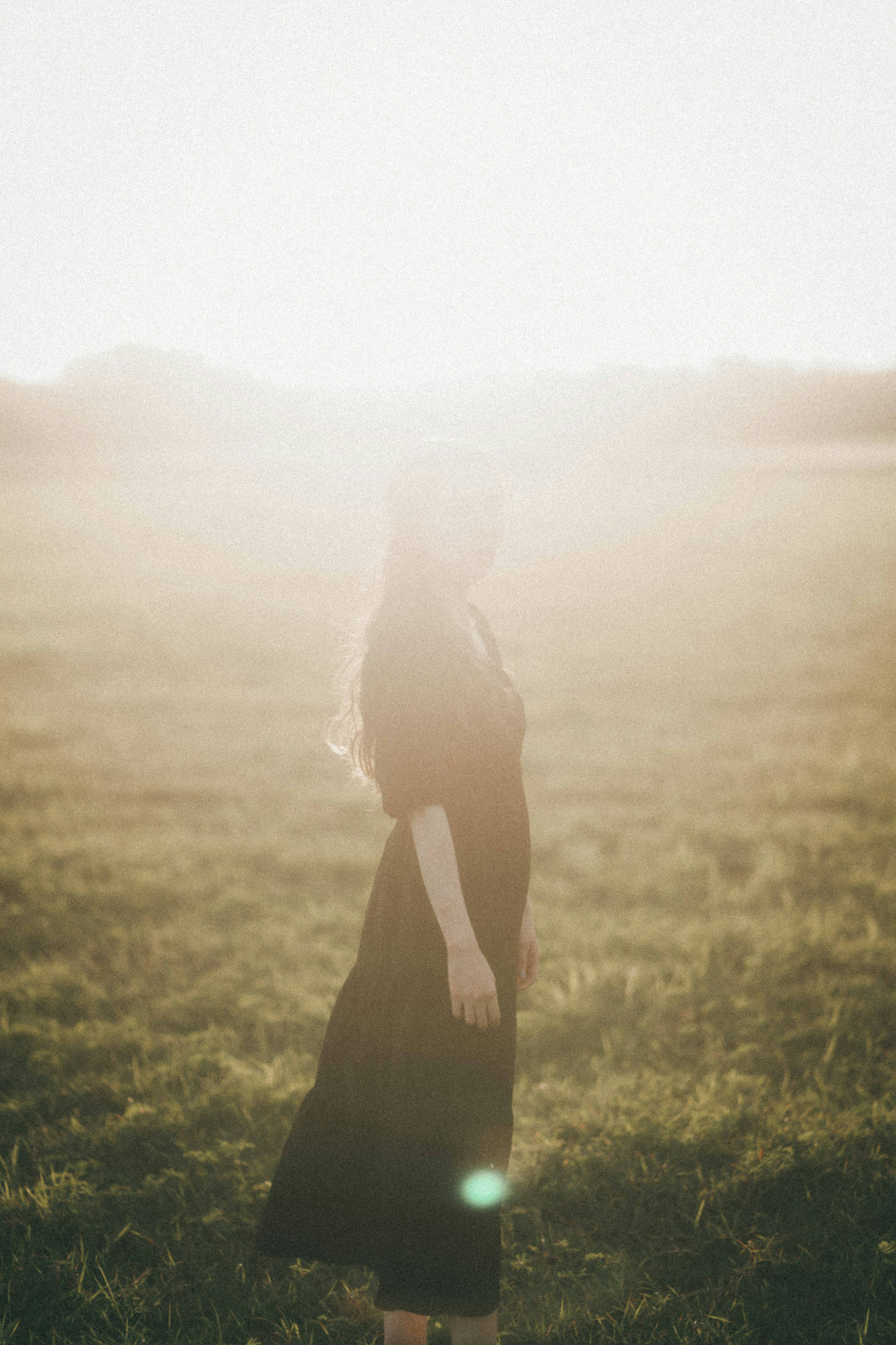 Silhouette d'une femme se tenant en contre-jour atmosphère sereine dans une prairie verte