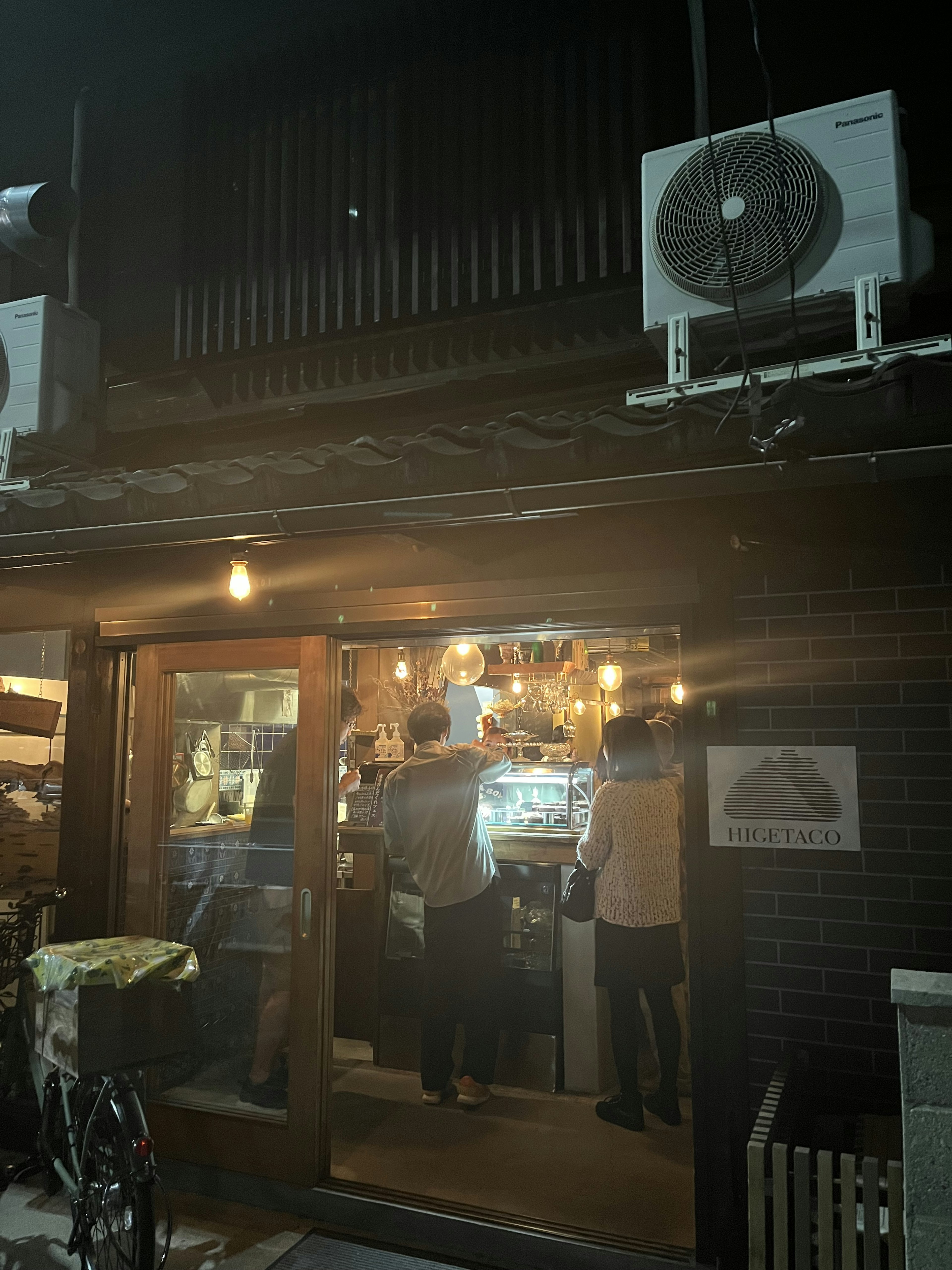 Façade d'un restaurant la nuit avec des lumières allumées montrant l'intérieur