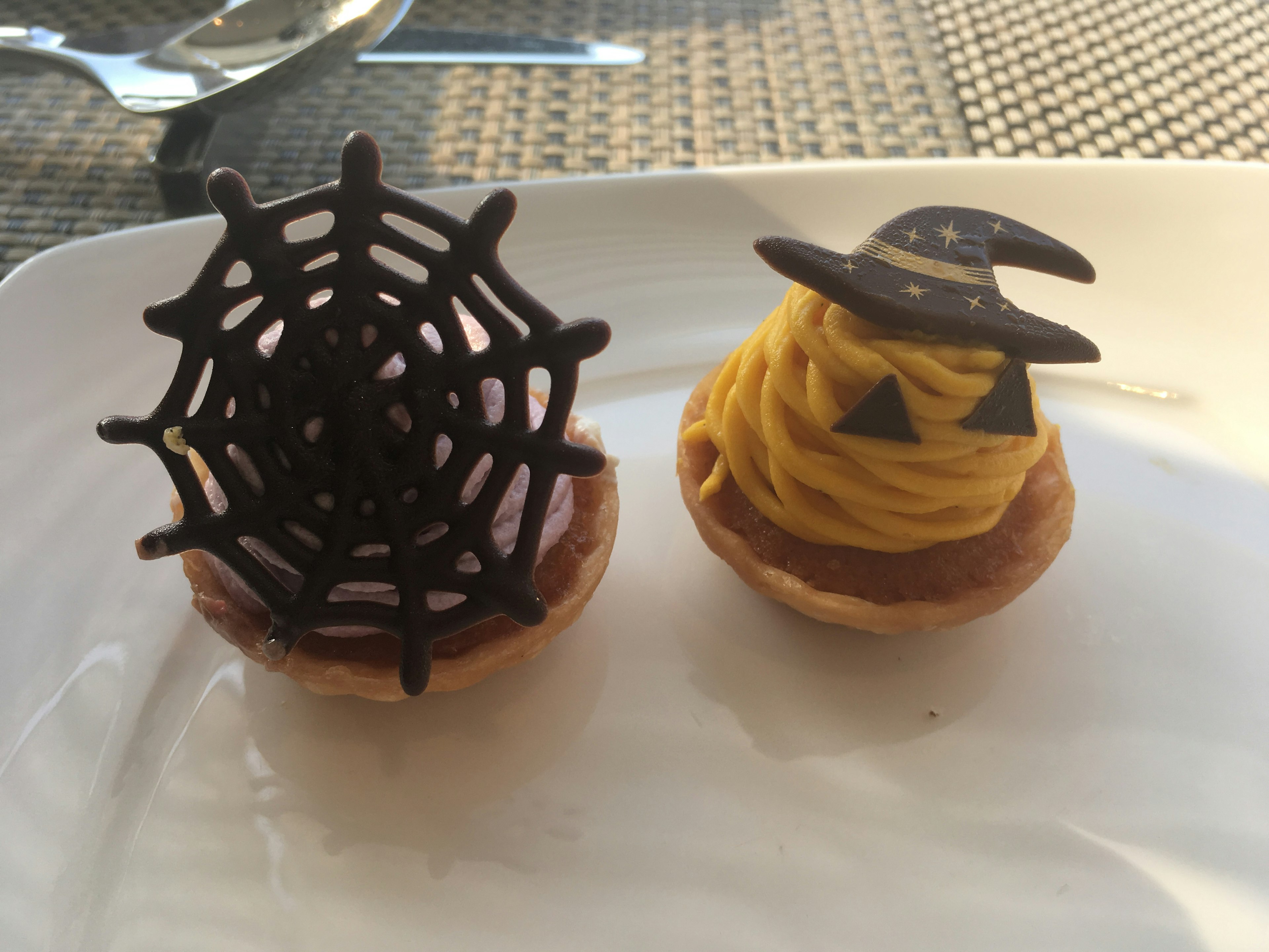 Two Halloween-themed desserts featuring a chocolate spider web and a witch hat design