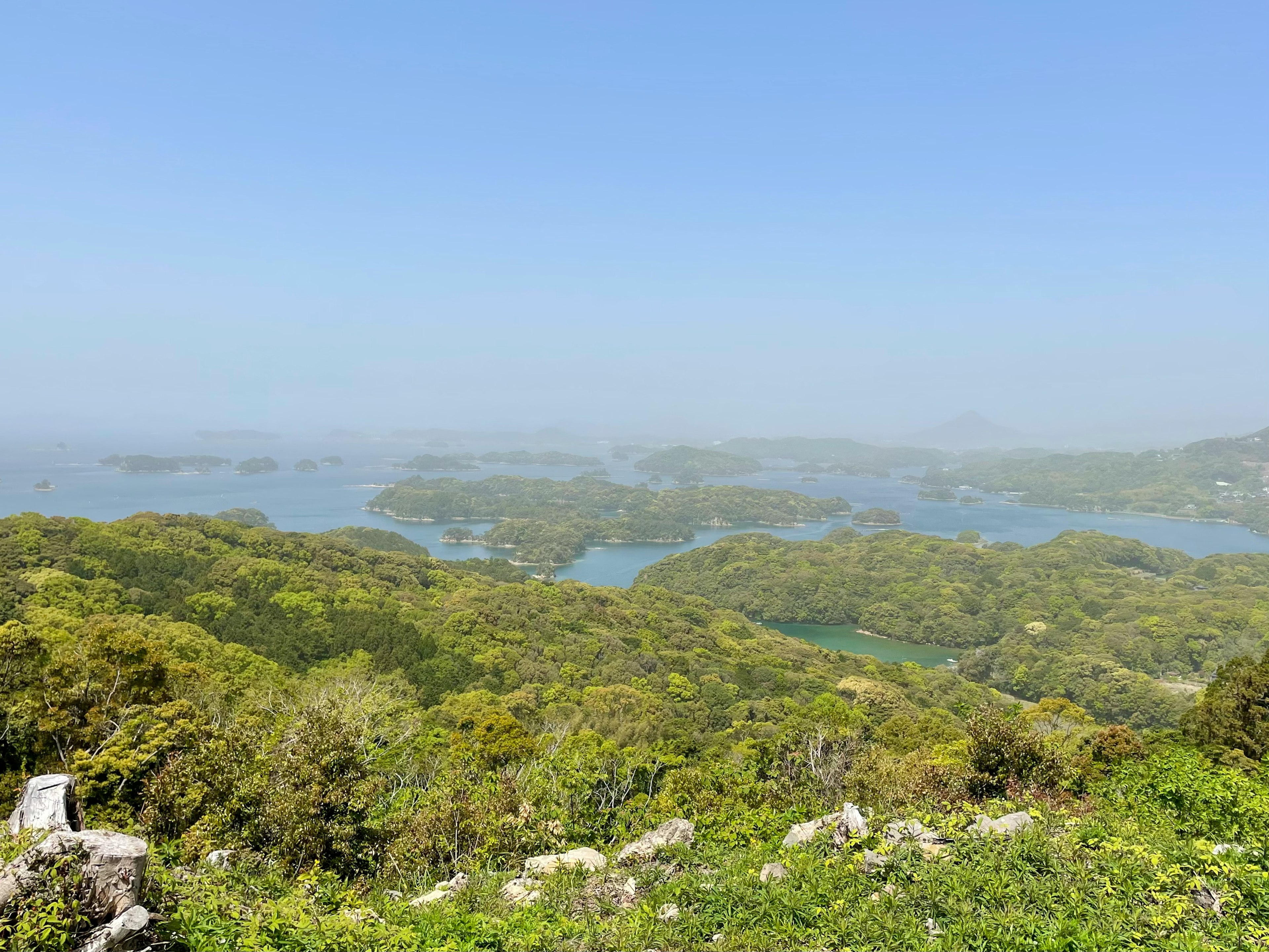 Vista panoramica di colline verdi e cielo blu con corpi idrici in lontananza