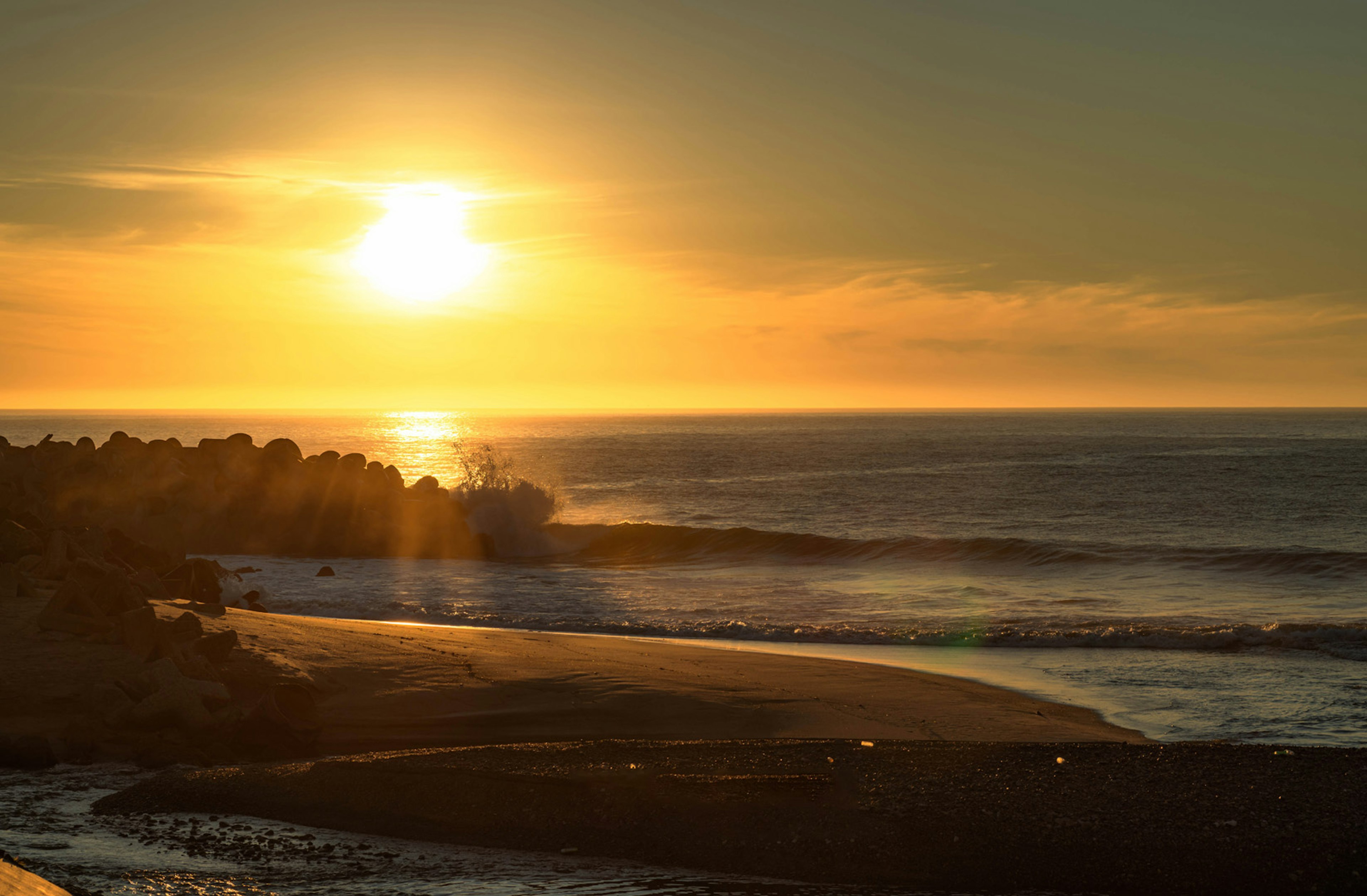 Magnifique coucher de soleil sur l'océan avec une plage de sable noir et des vagues