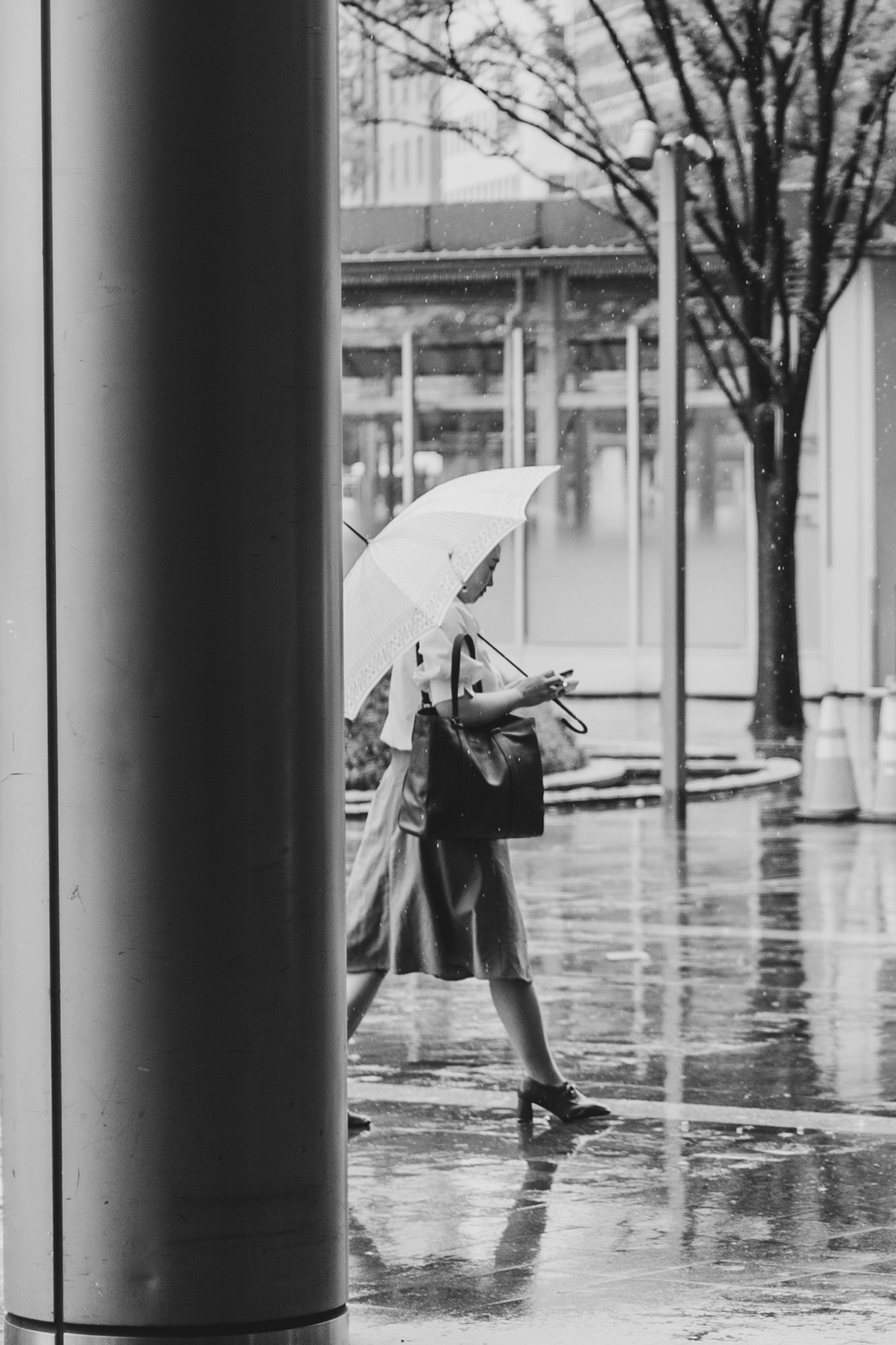 雨の中を歩く女性が傘をさしているモノクロの写真